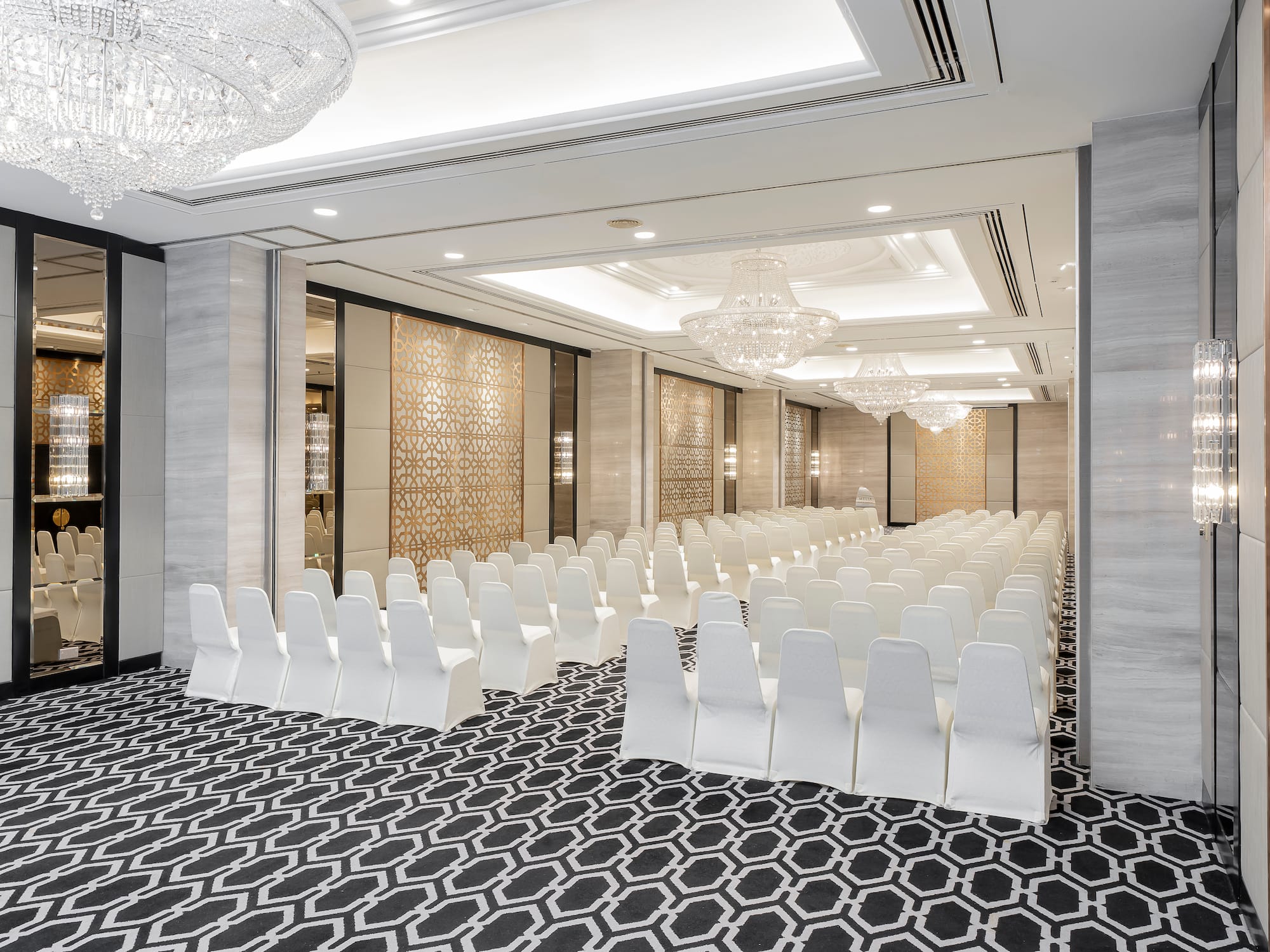 a room with white chairs and chandeliers