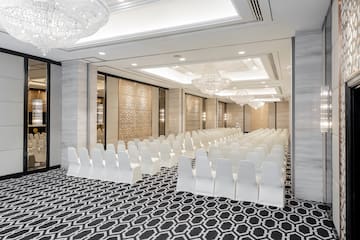 a room with white chairs and chandeliers