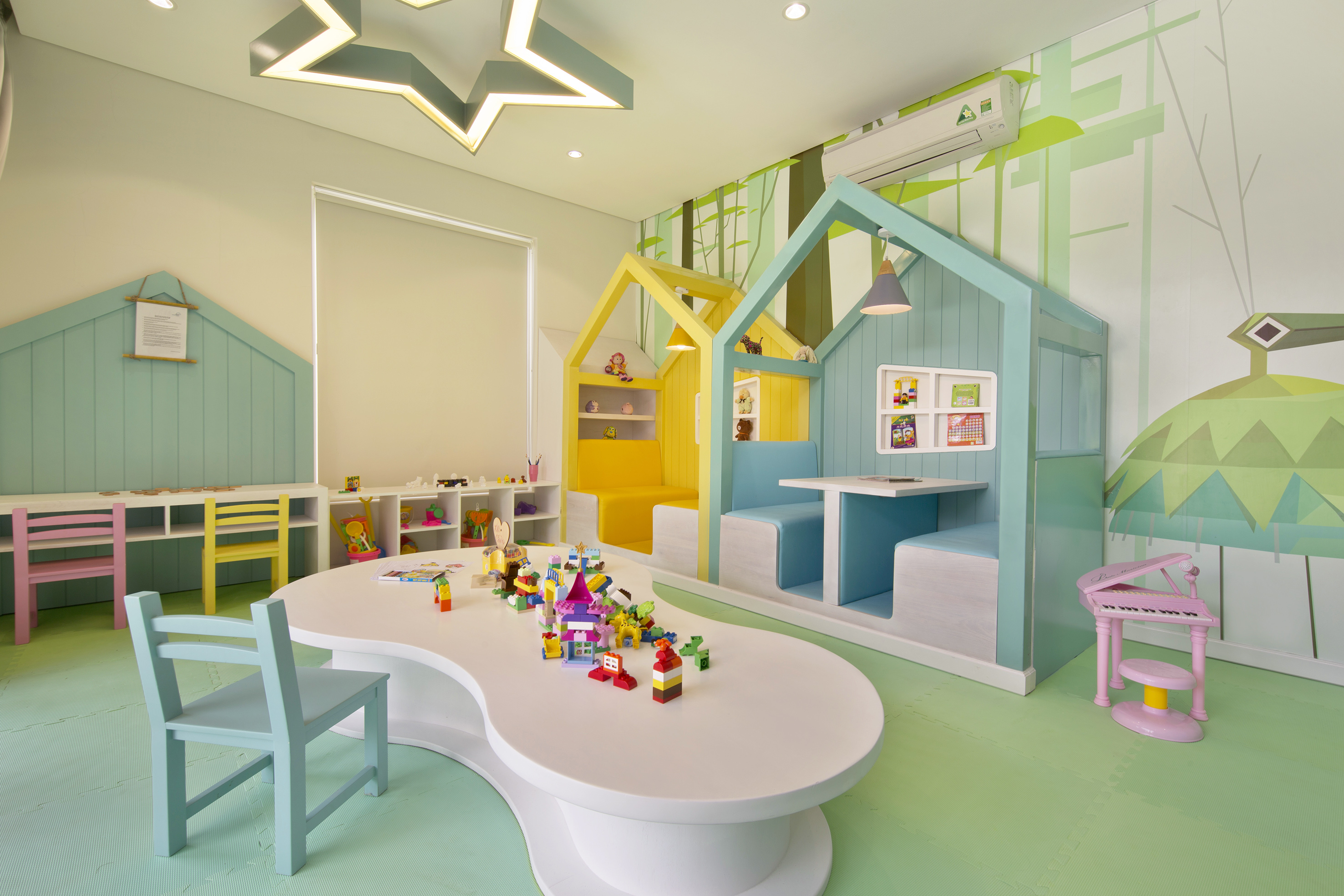 Colorful children's playroom with house booths, blocks, green forest mural.