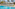 Resort swimming pool with white lounge chairs, umbrellas, and palm trees.