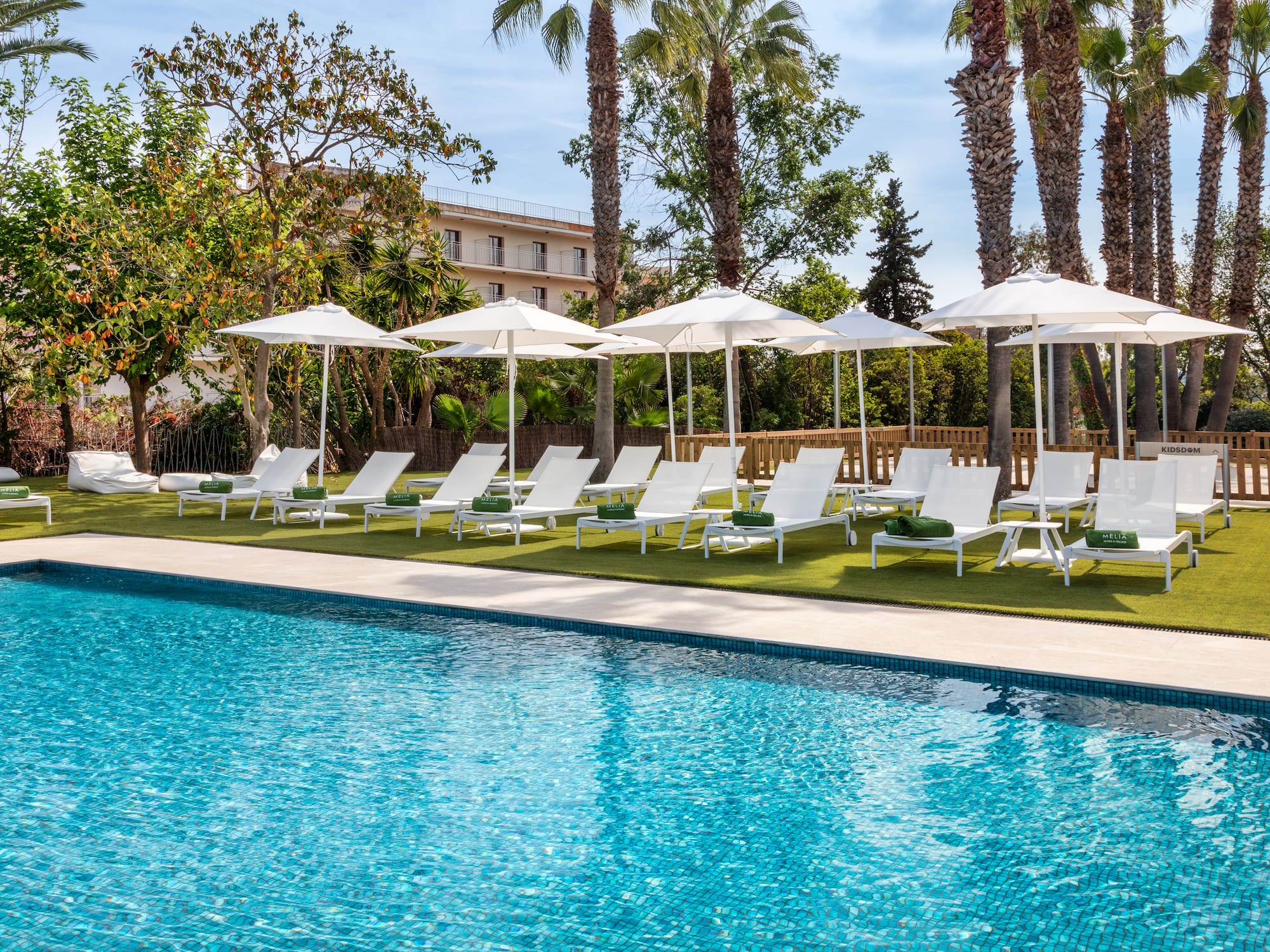 a pool with white umbrellas and lounge chairs