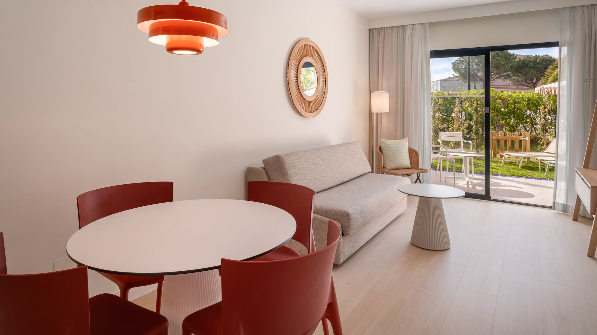 Modern living room with dining table, sofa, and outdoor garden patio view.