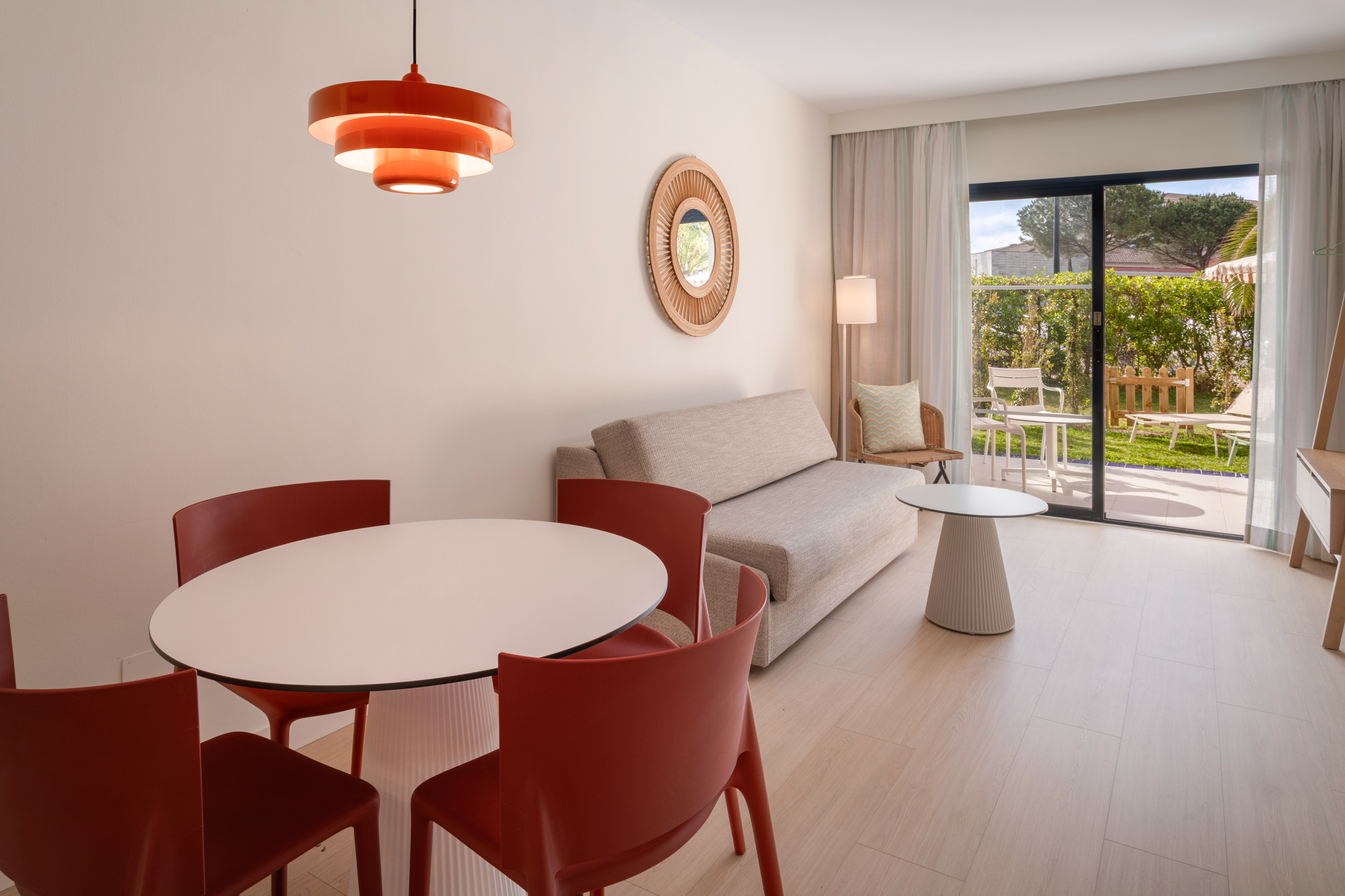 Modern living room with dining table, sofa, and outdoor garden patio view.