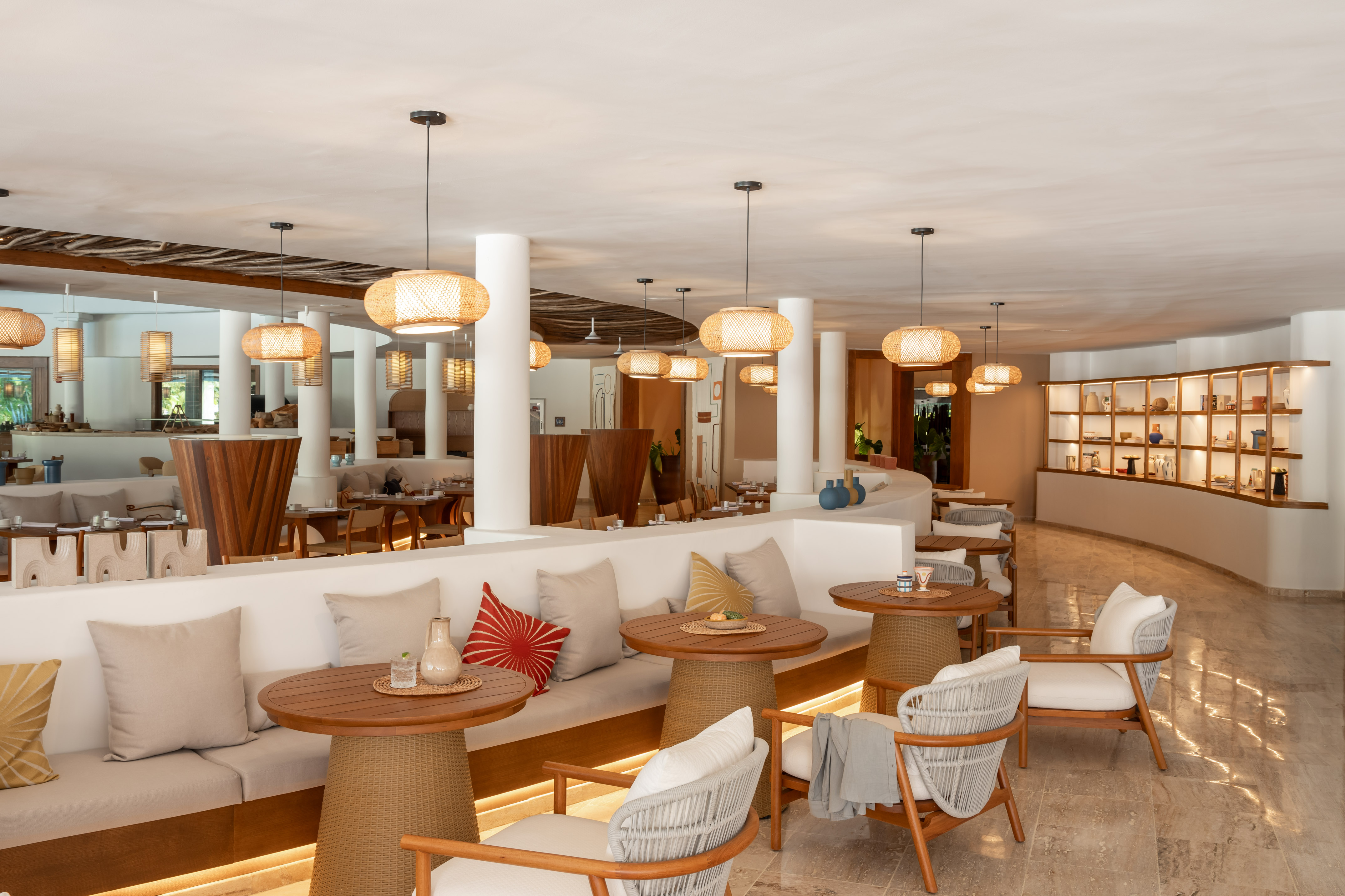 Resort dining room with rattan lights, wood tables, and modern lounge seating.