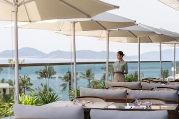 a woman holding a tray of food under umbrellas