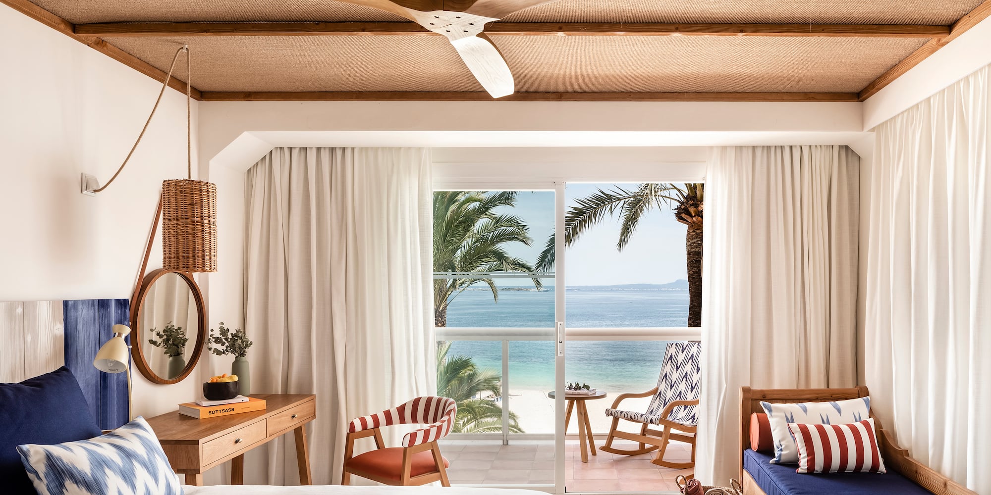 a room with a bed and chairs and a fan