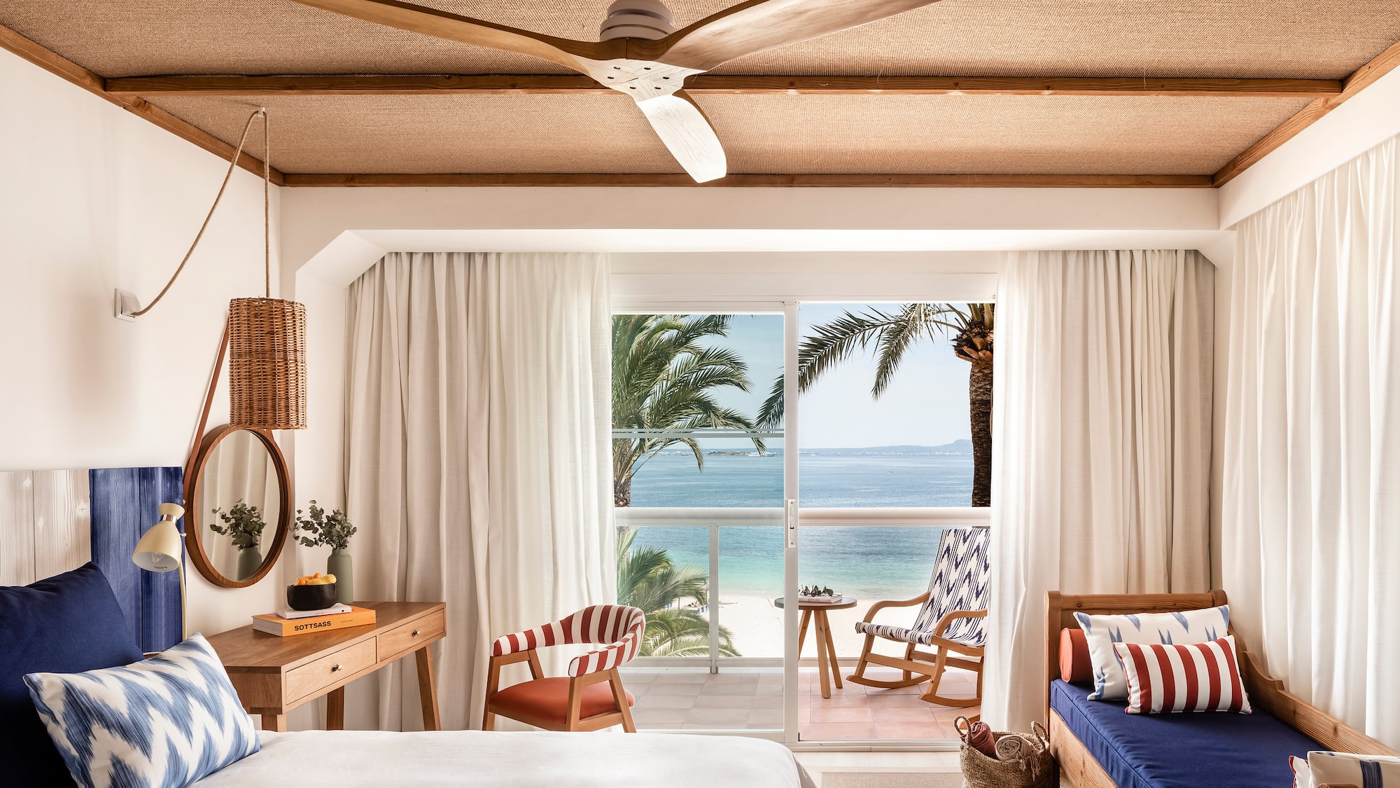 a room with a bed and chairs and a fan