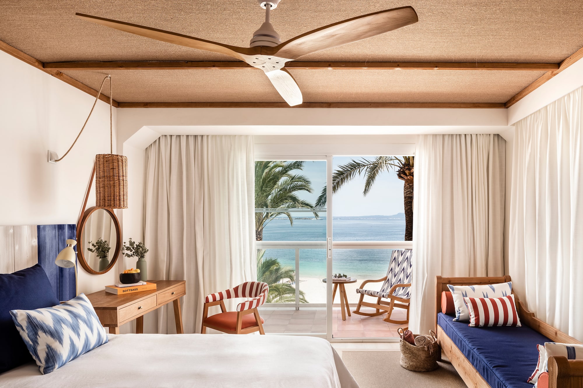 a room with a bed and chairs and a fan