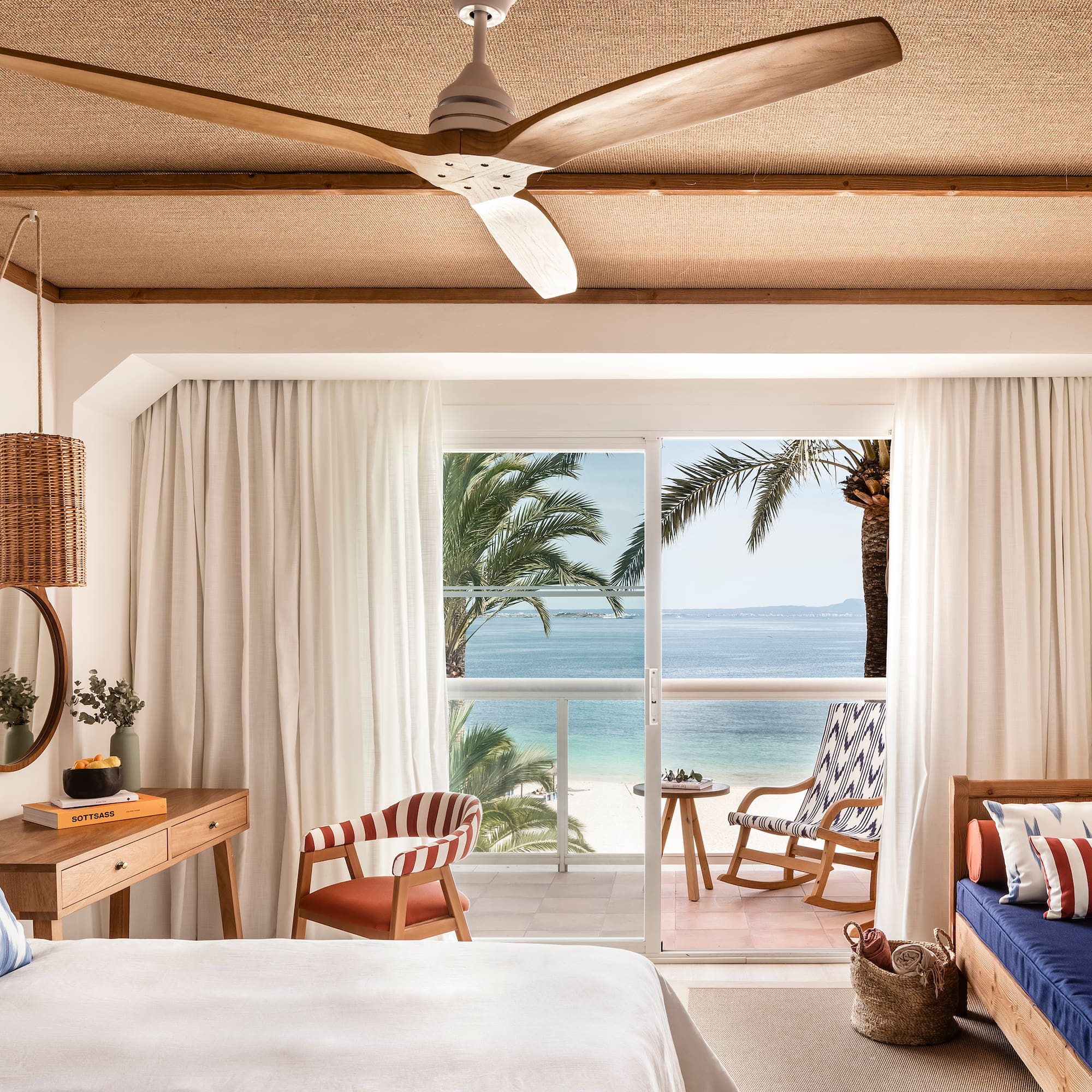 a room with a bed and chairs and a fan