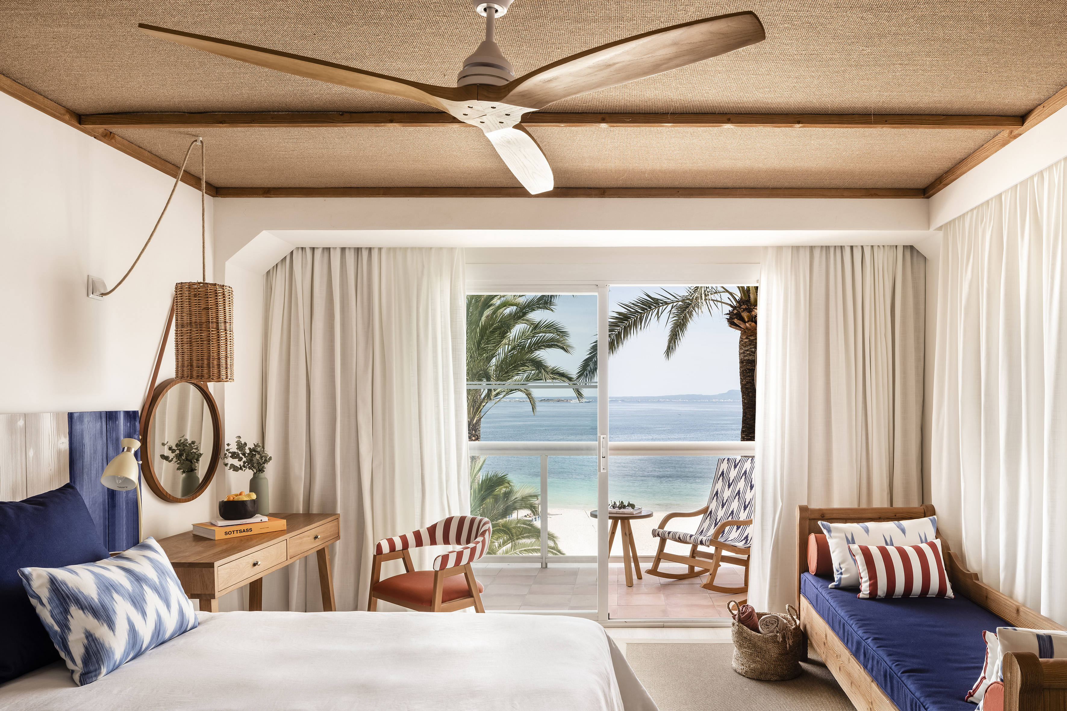 Beachfront bedroom with ocean view balcony, tropical hotel room decor.