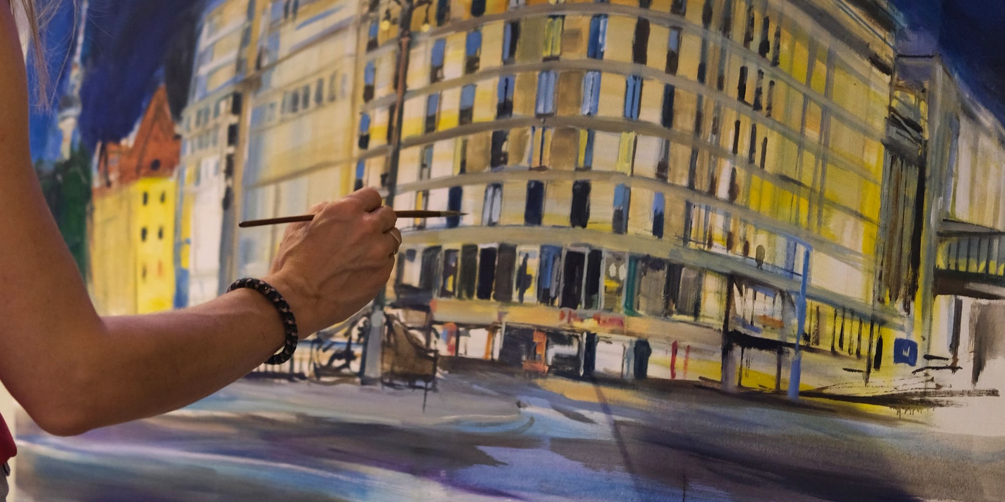 Artist painting a vibrant Meliá hotel cityscape at night on an easel.