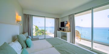 a room with a large bed and a glass door with a view of the ocean