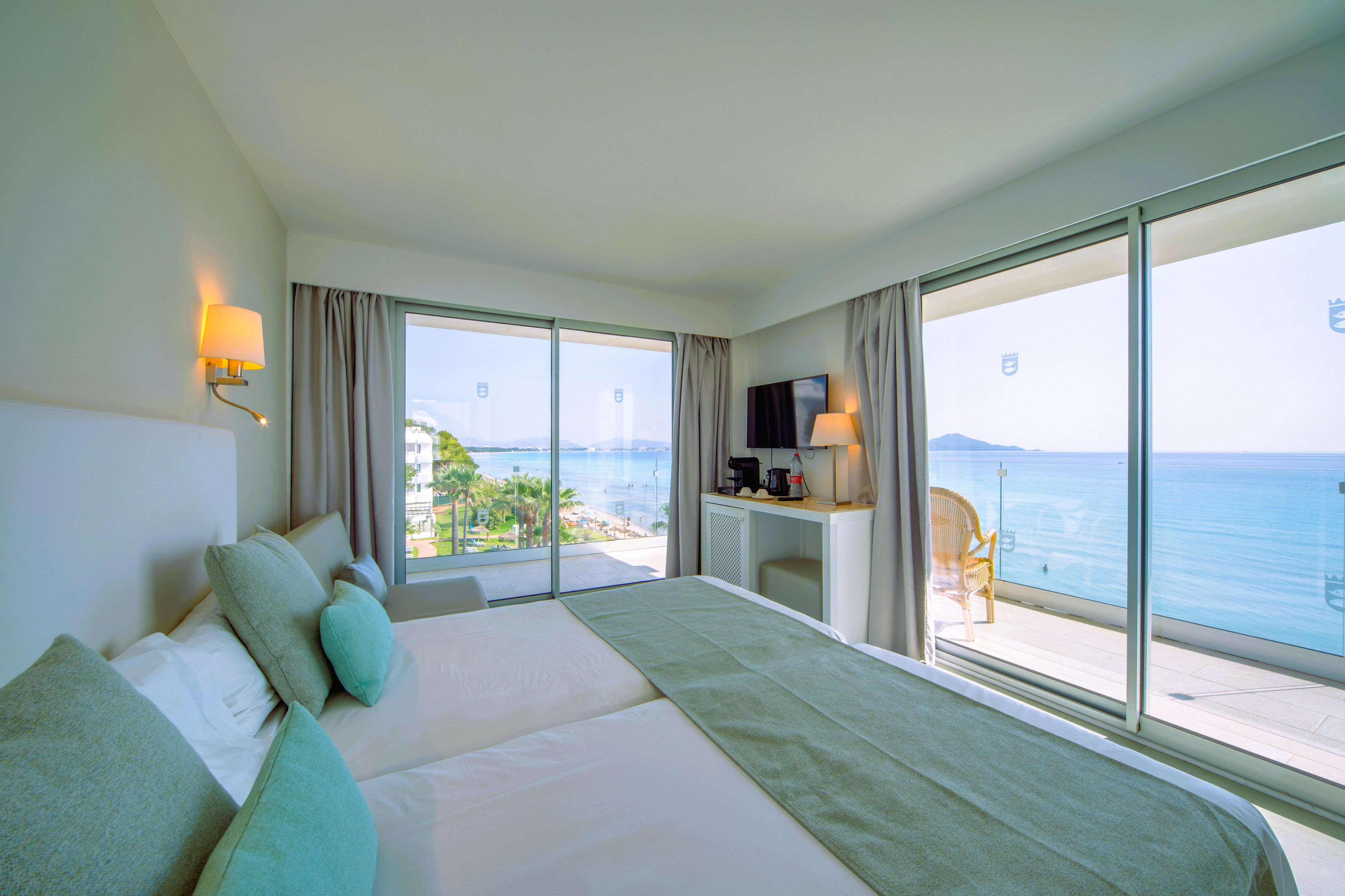 a room with a large bed and a glass door with a view of the ocean