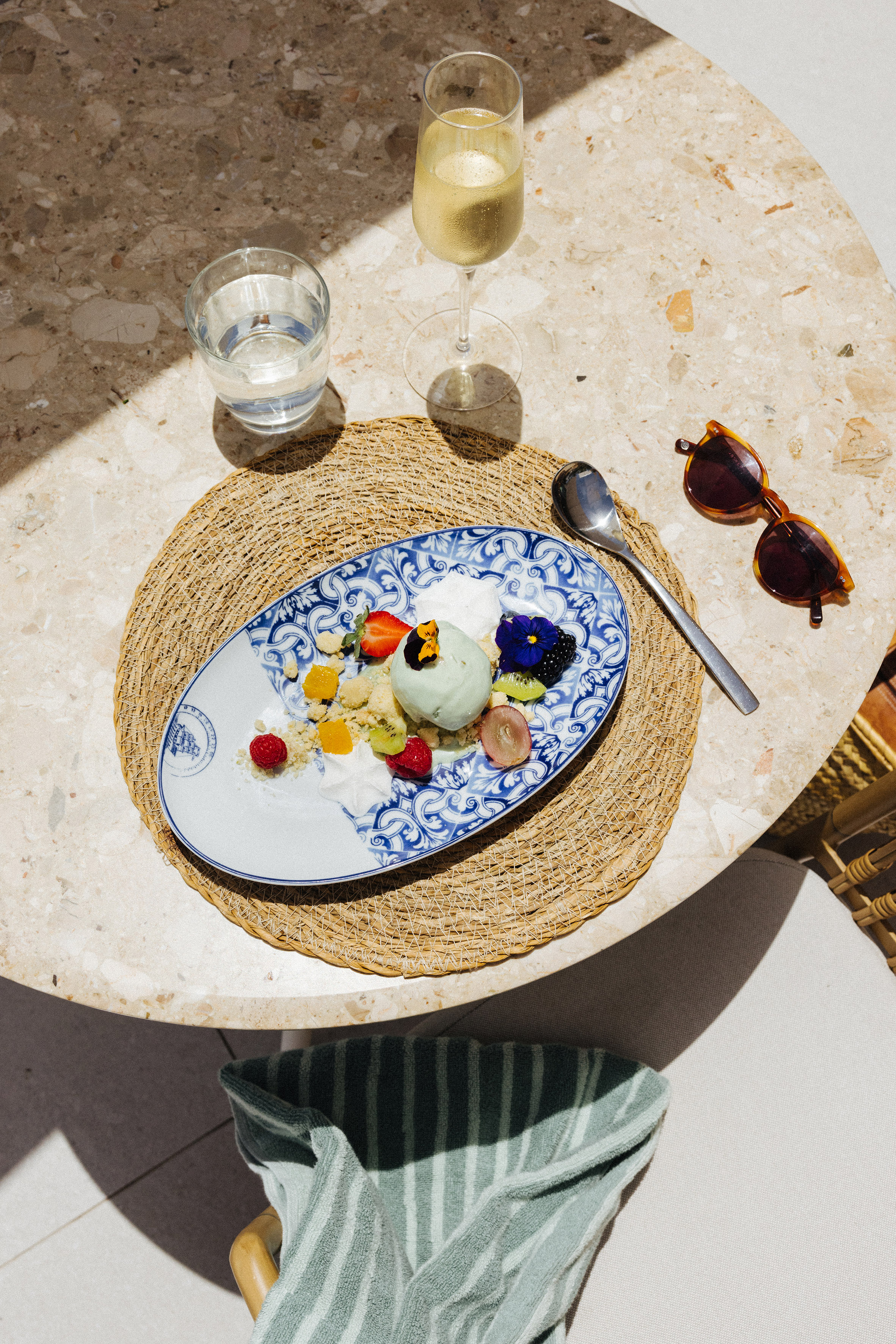 Green ice cream dessert with fresh fruit, edible flowers, champagne on sunny table.