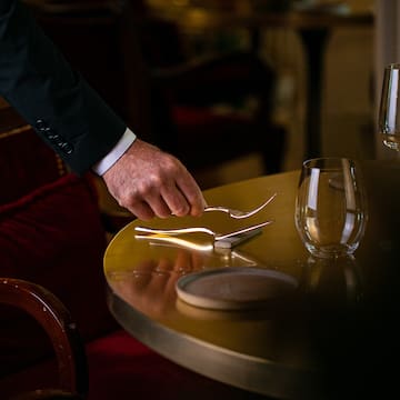 a hand holding a fork and knife on a table