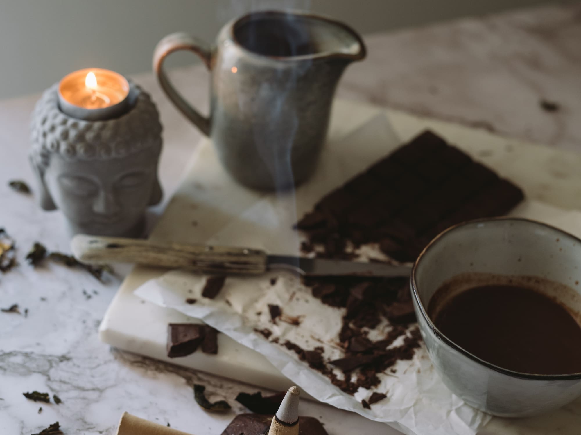 a cup of coffee and a candle on a marble surface