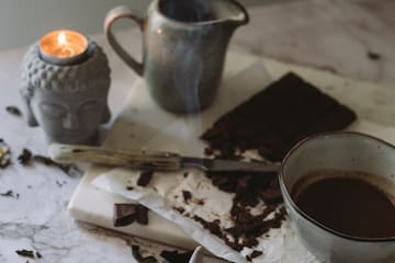 a cup of coffee and a candle on a marble surface