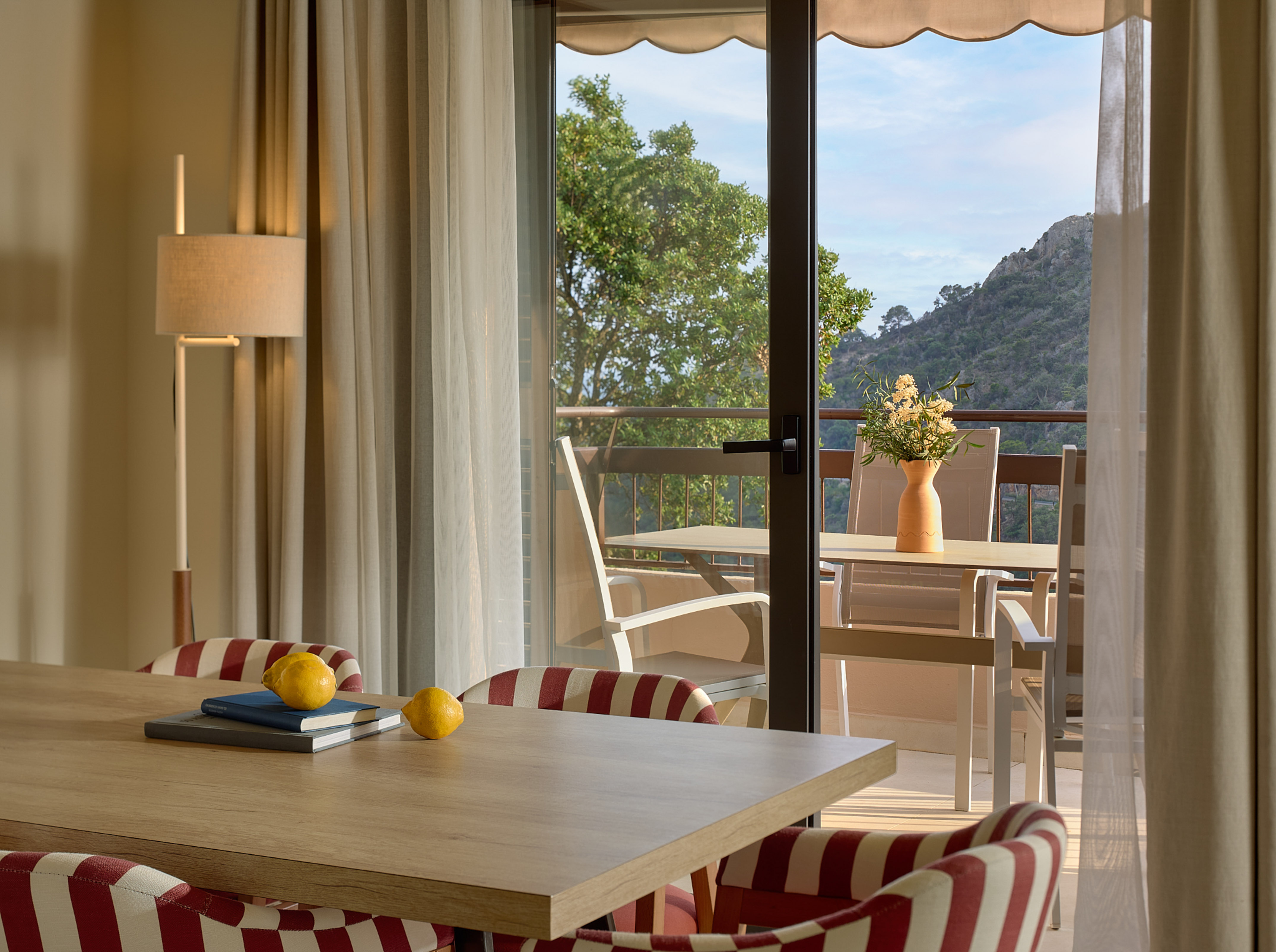 Dining area with balcony access, mountain view, and lemons on table.