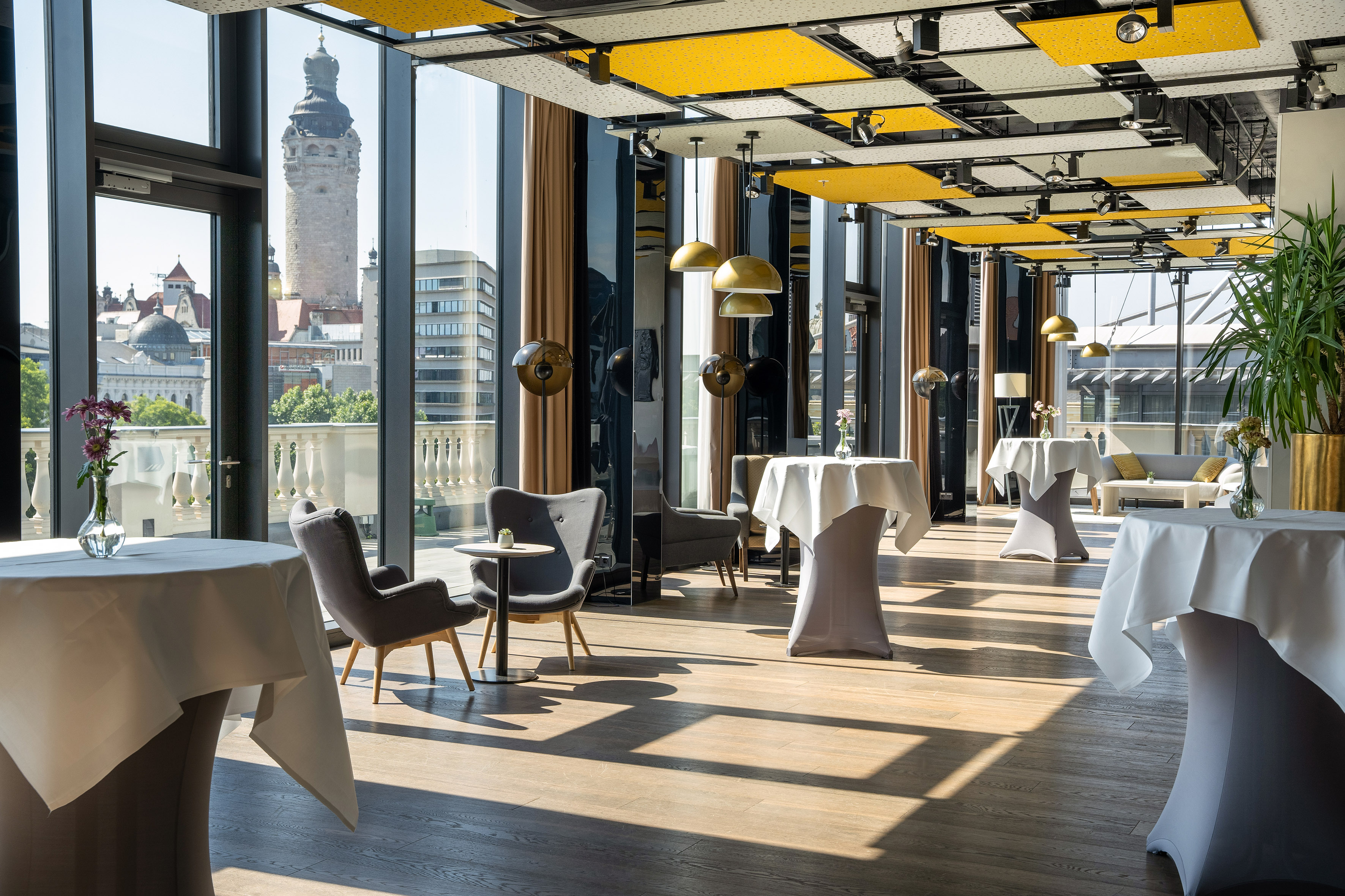 Panoramic event lounge with Leipzig tower view, modern design, high-top tables.