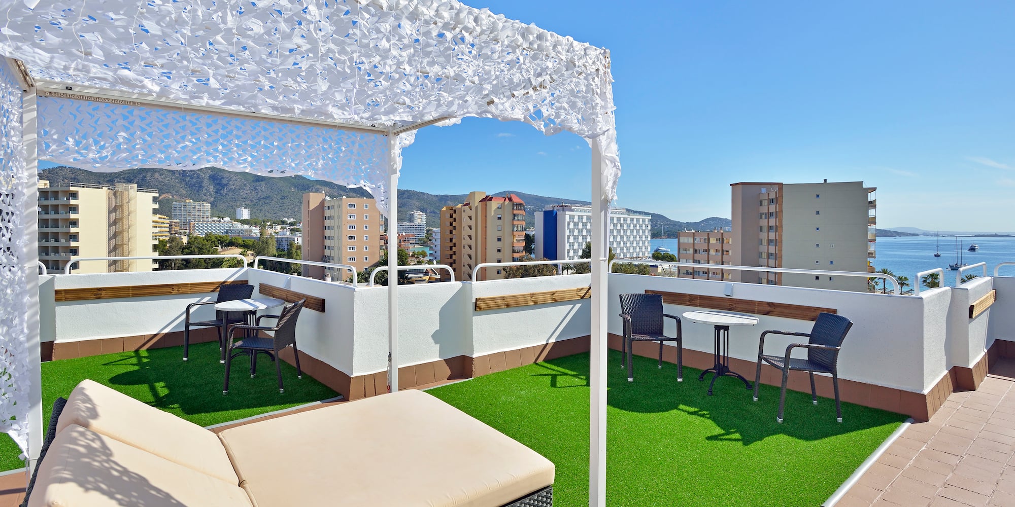 a patio with a white canopy and chairs on a rooftop
