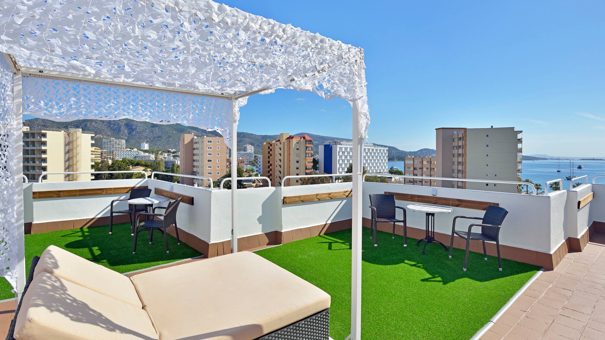 a patio with a white canopy and chairs on a rooftop