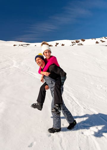 a man carrying a woman on his back in the snow