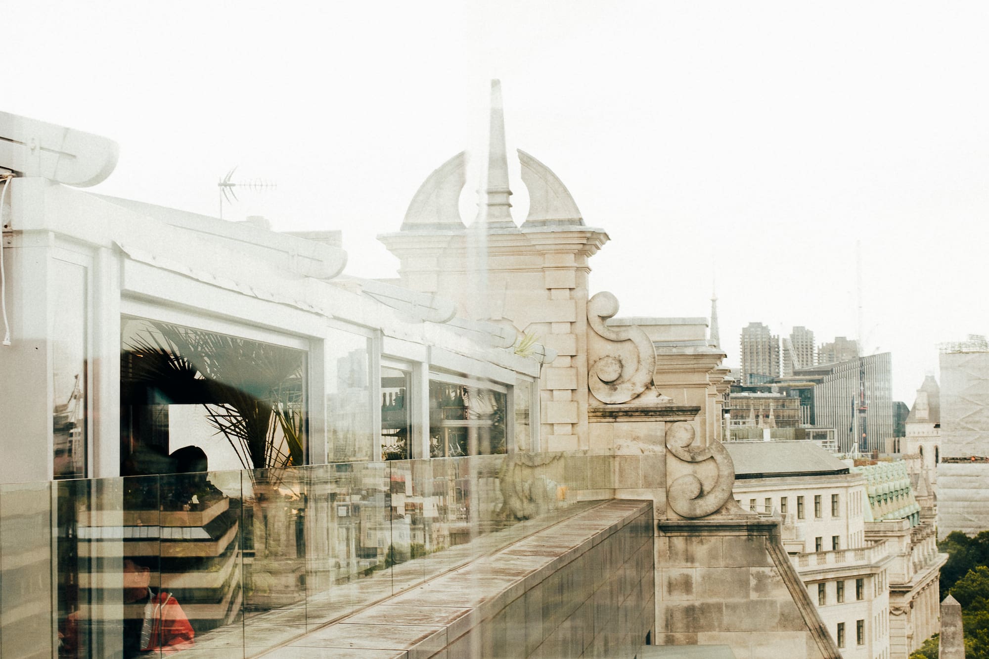 Rooftop terrace with glass railing, historic architecture, and city skyline.