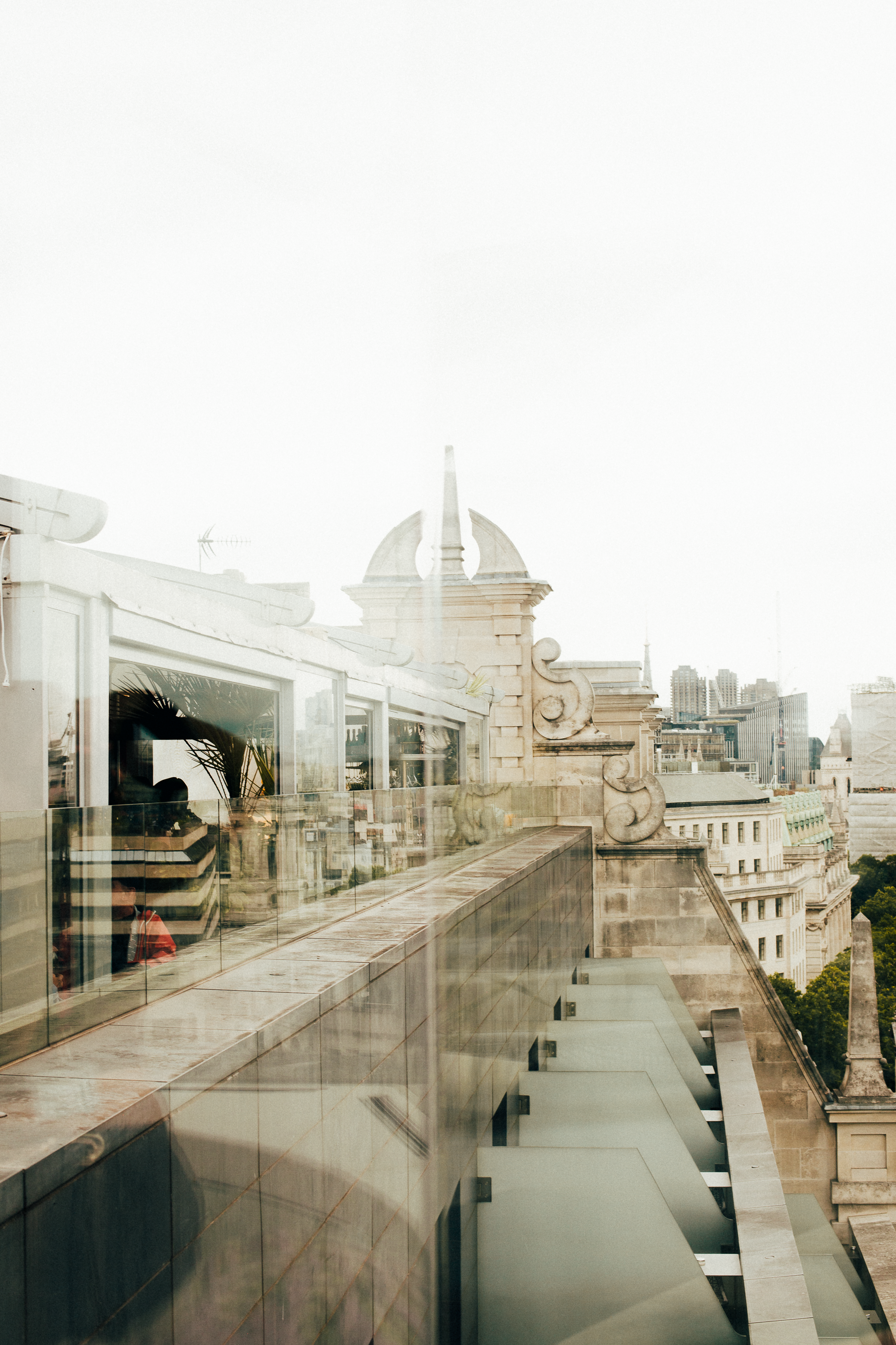 Rooftop terrace with glass railing, historic architecture, and city skyline.