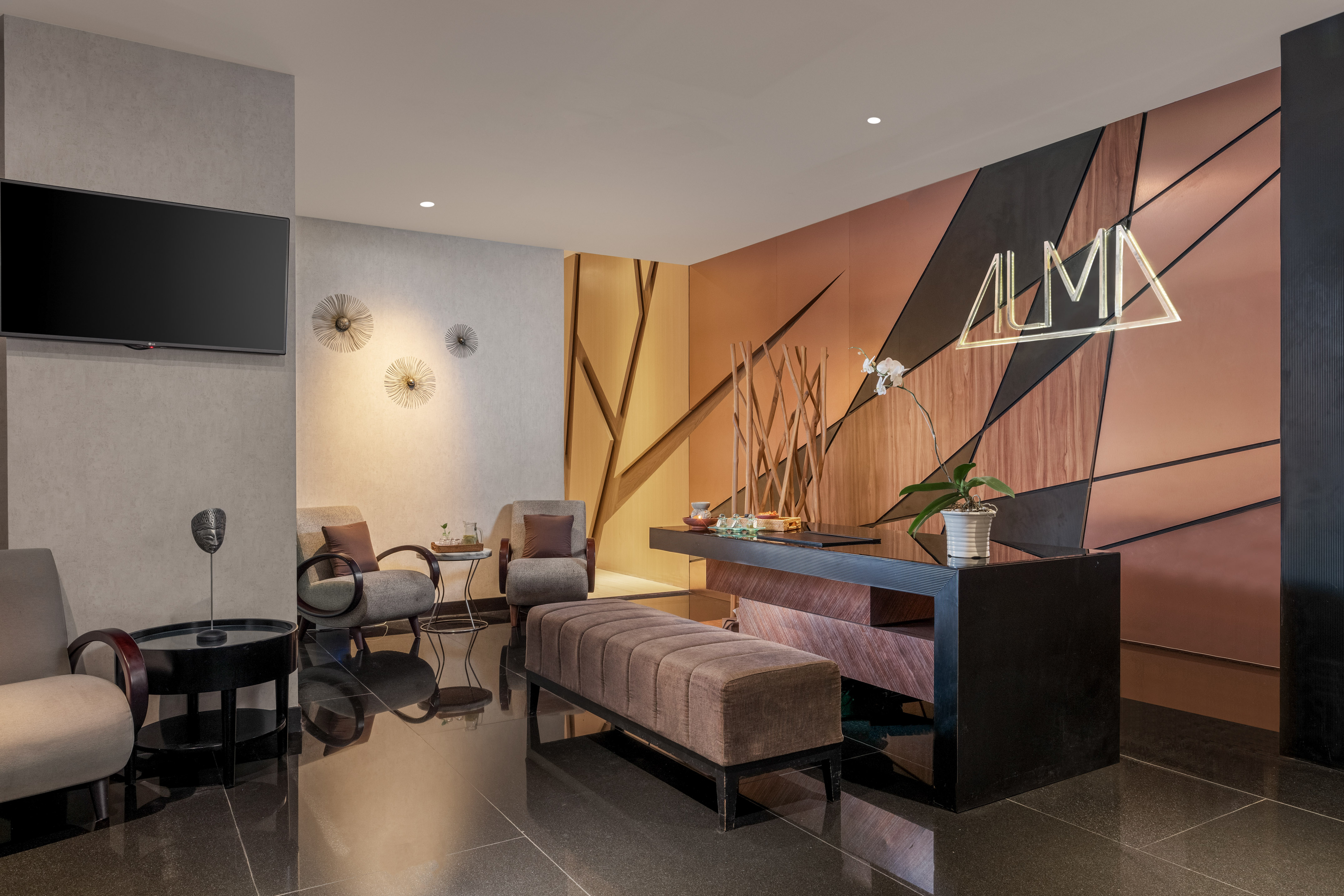 ALMA hotel reception with modern desk, lounge seating, geometric wall decor.