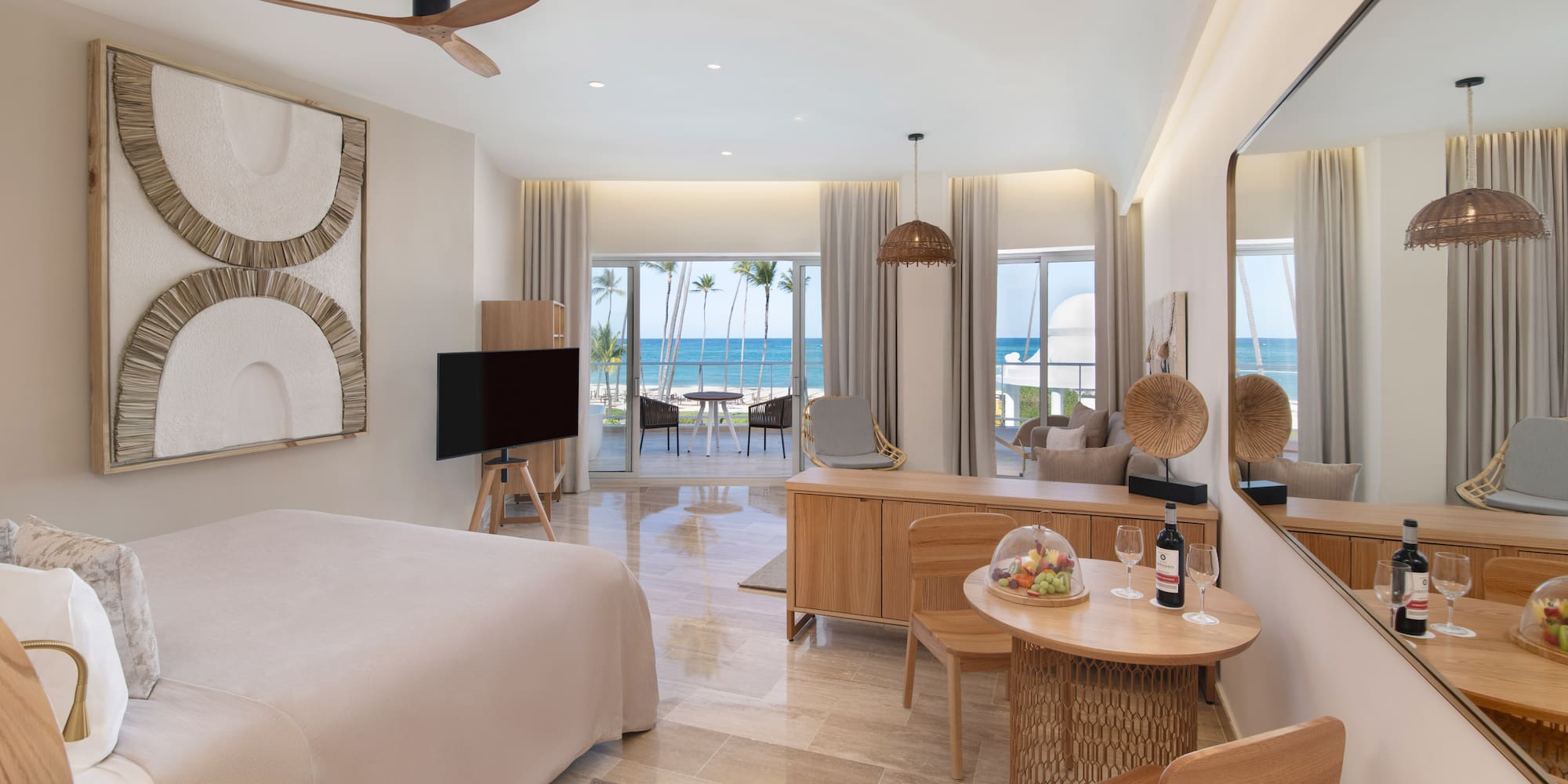 Modern luxury hotel room with beachfront ocean view, king bed, and balcony.