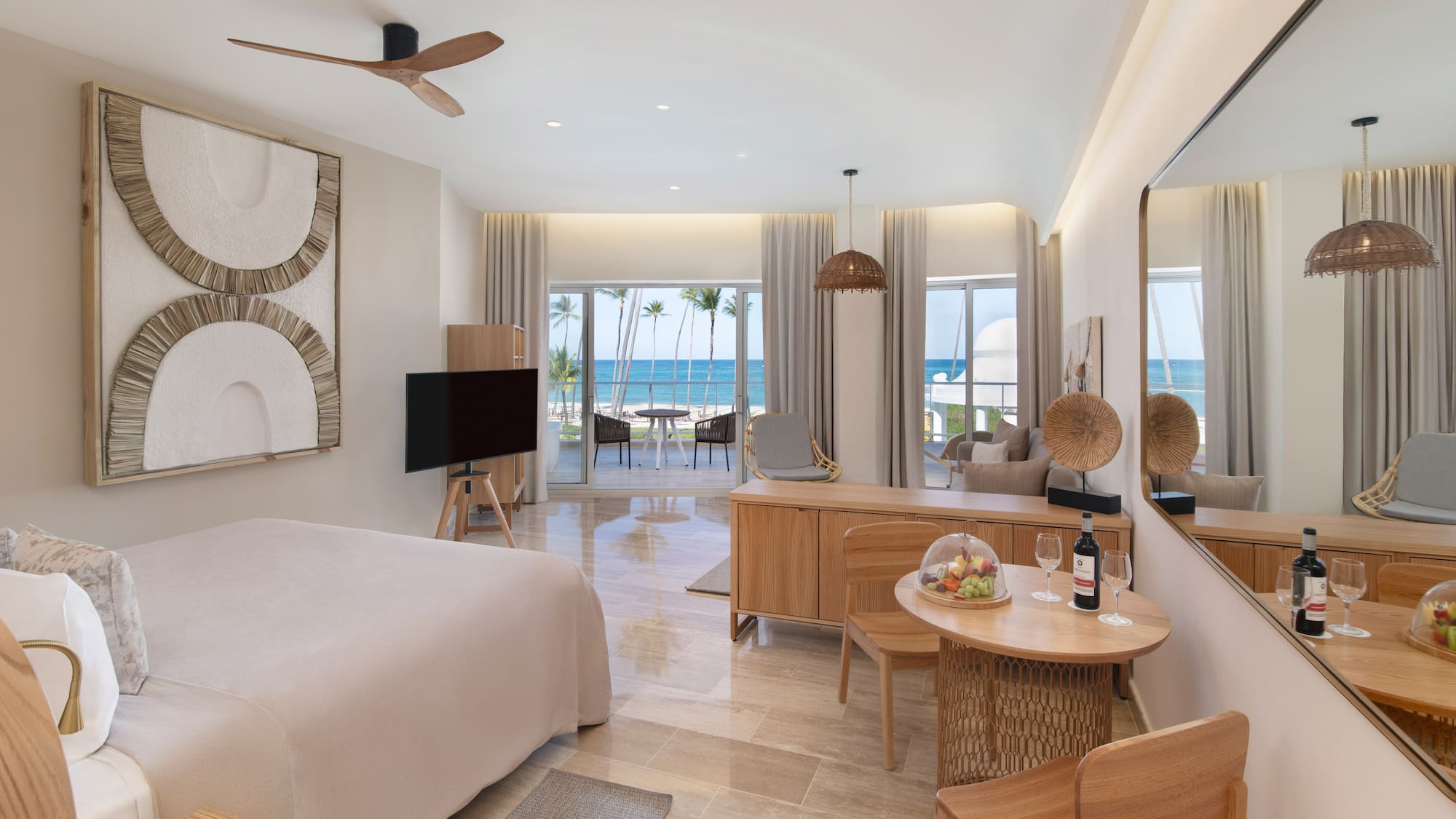 Modern luxury hotel room with beachfront ocean view, king bed, and balcony.