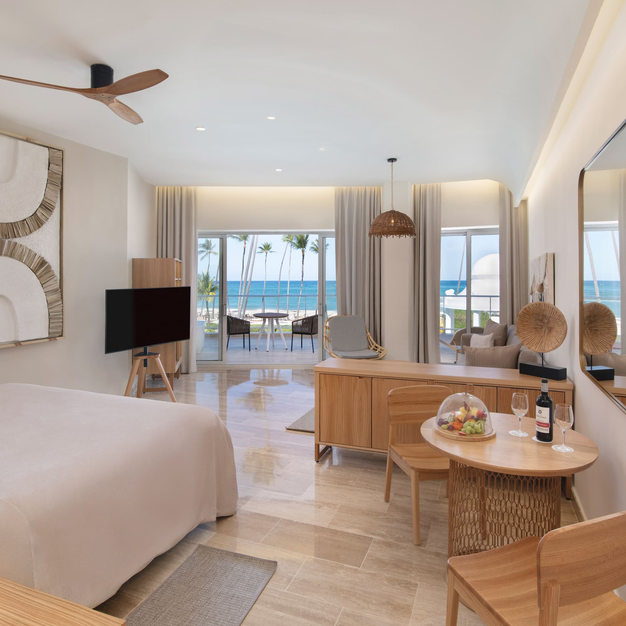 Modern luxury hotel room with beachfront ocean view, king bed, and balcony.