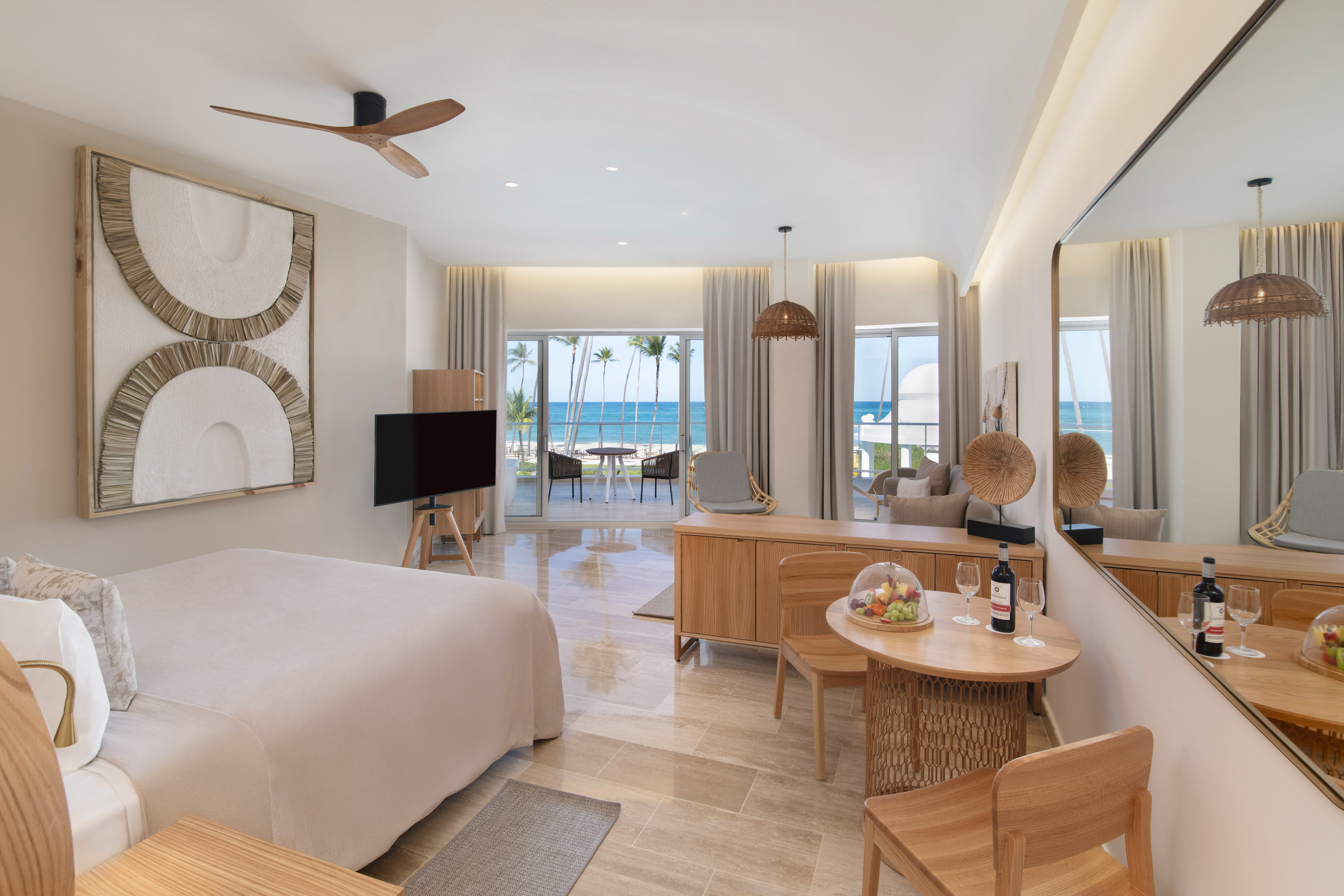 Modern luxury hotel room with beachfront ocean view, king bed, and balcony.