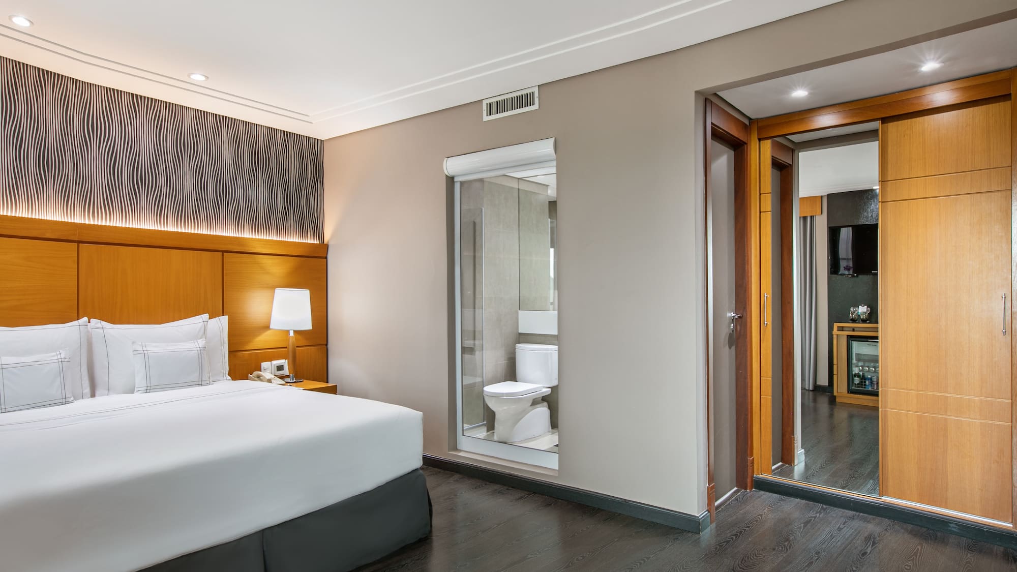 a bedroom with a wood floor and a white bed