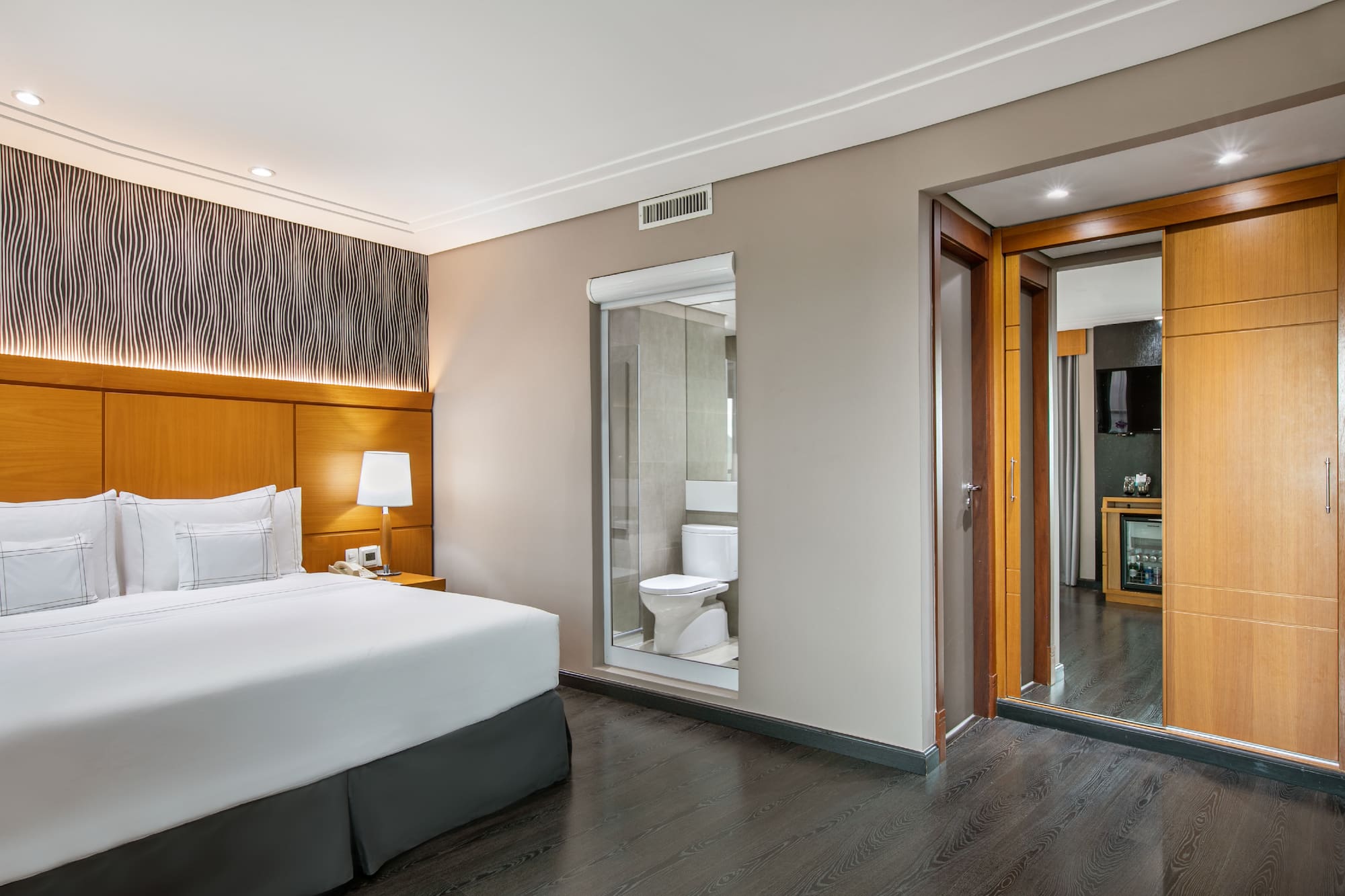 a bedroom with a wood floor and a white bed