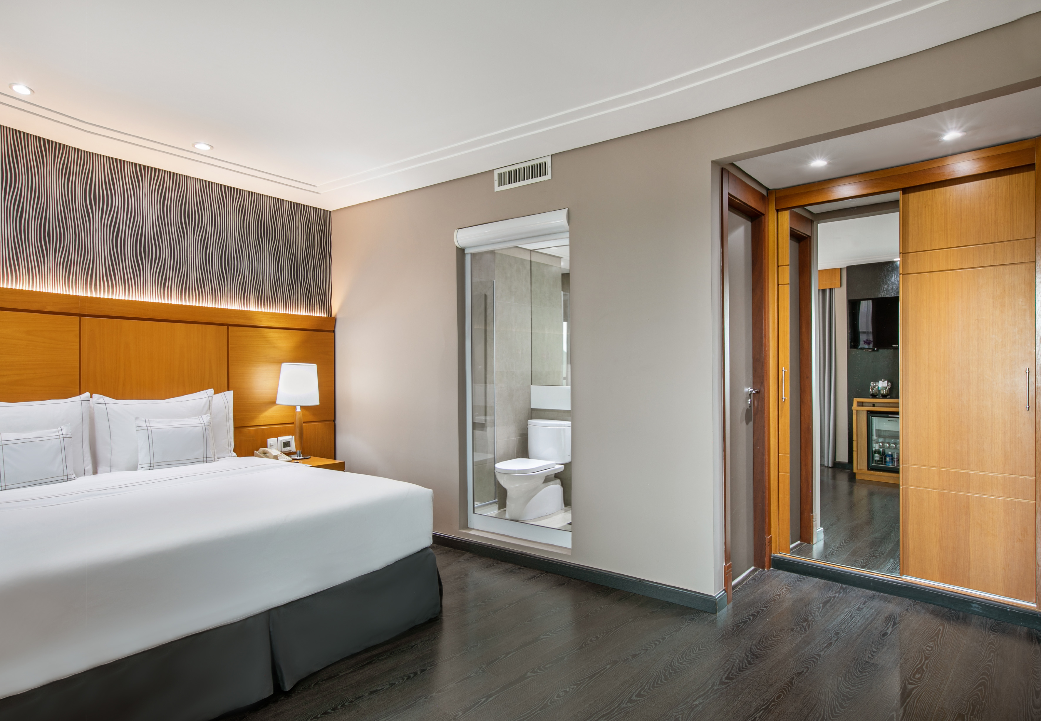 a bedroom with a wood floor and a white bed