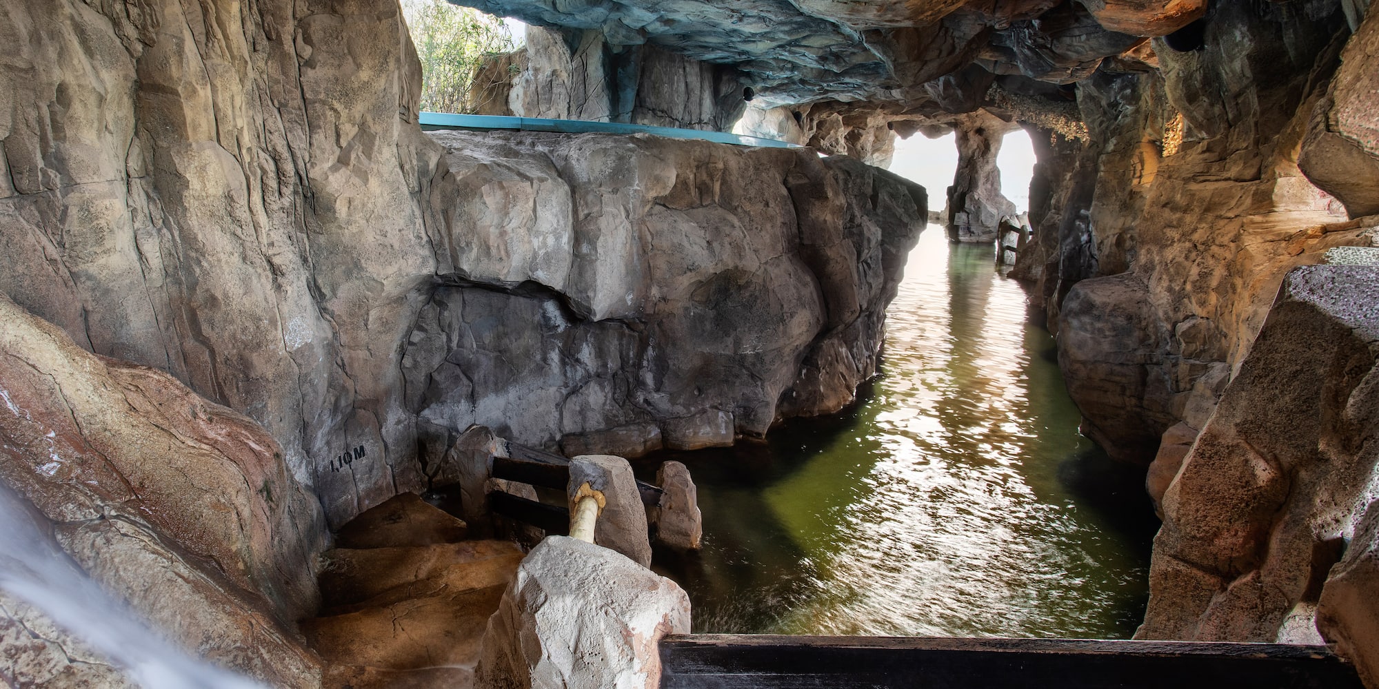 Grotto interior with water channel, waterfall, light, and stone walls.