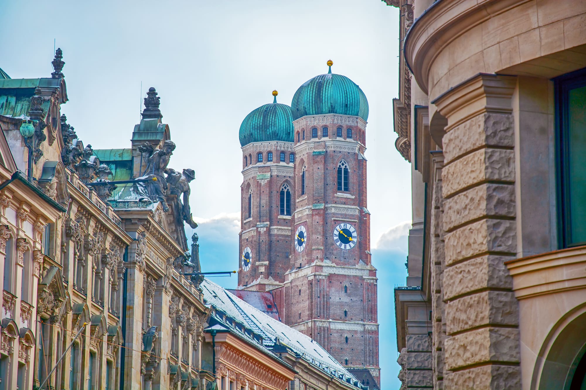 Frauenkirche Múnich: torres góticas de ladrillo, cúpulas verdes, edificios históricos.