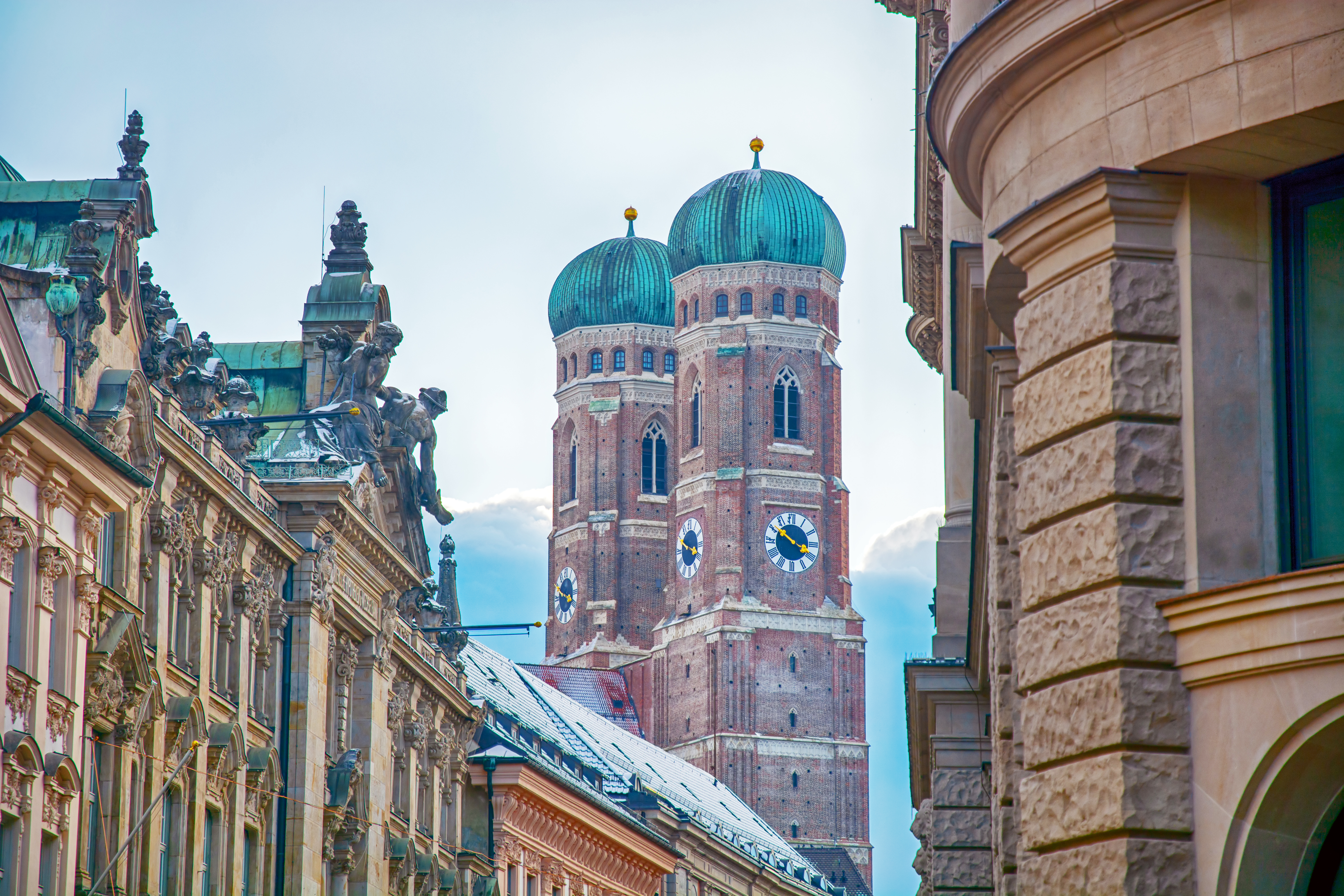 Frauenkirche Múnich: torres góticas de ladrillo, cúpulas verdes, edificios históricos.