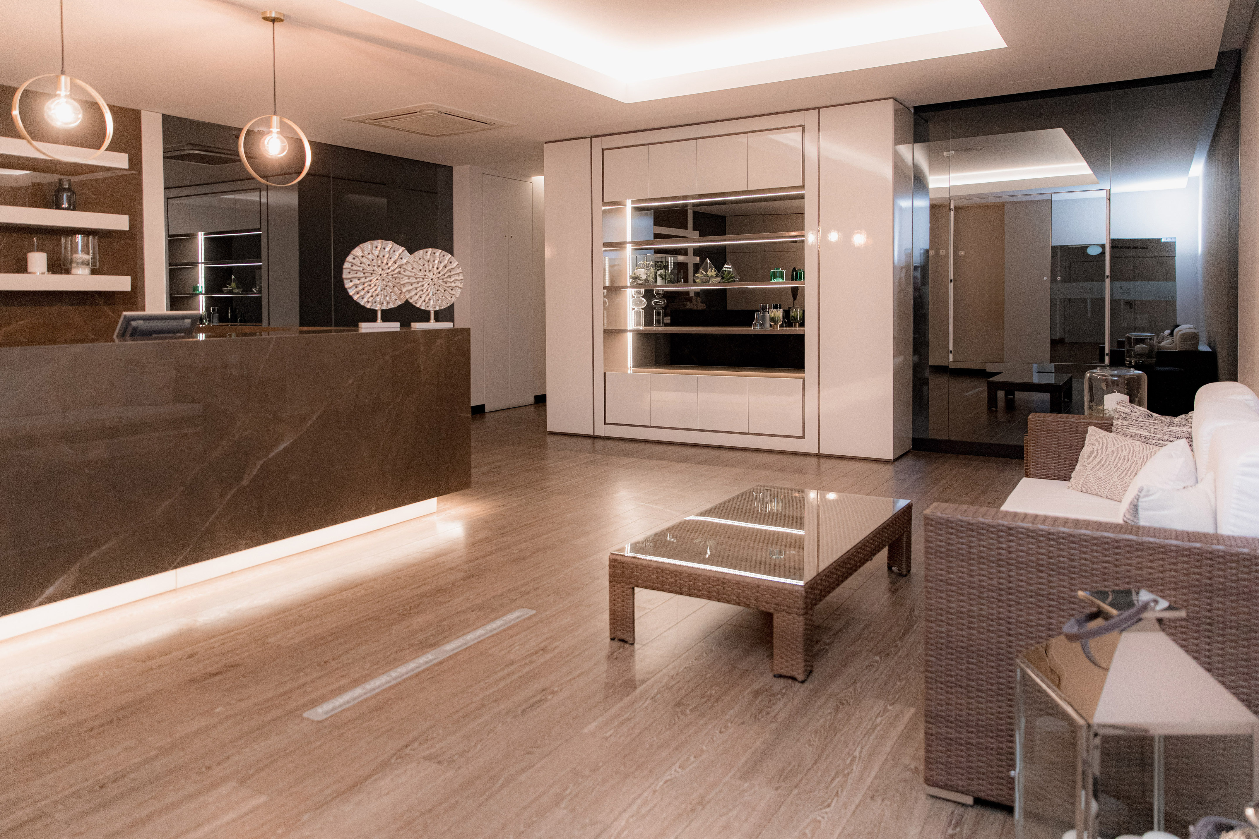 Modern spa reception lobby with marble counter, wicker sofa, and display shelves.