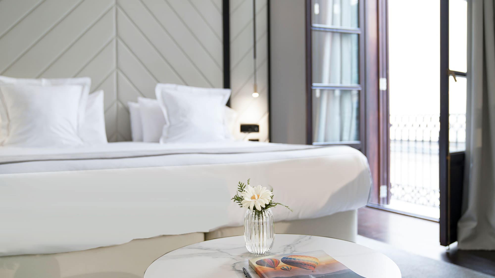 a table with a magazine and a pen in front of a bed