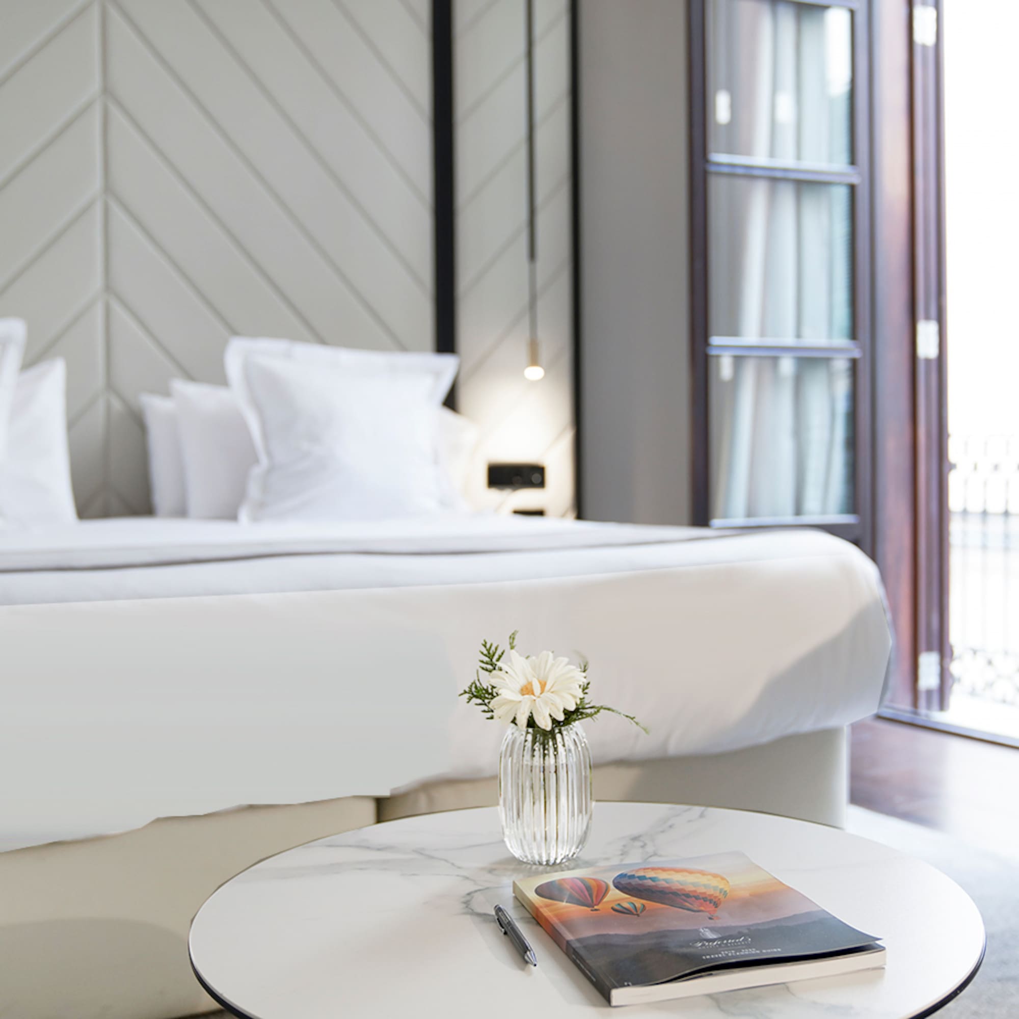 a table with a magazine and a pen in front of a bed