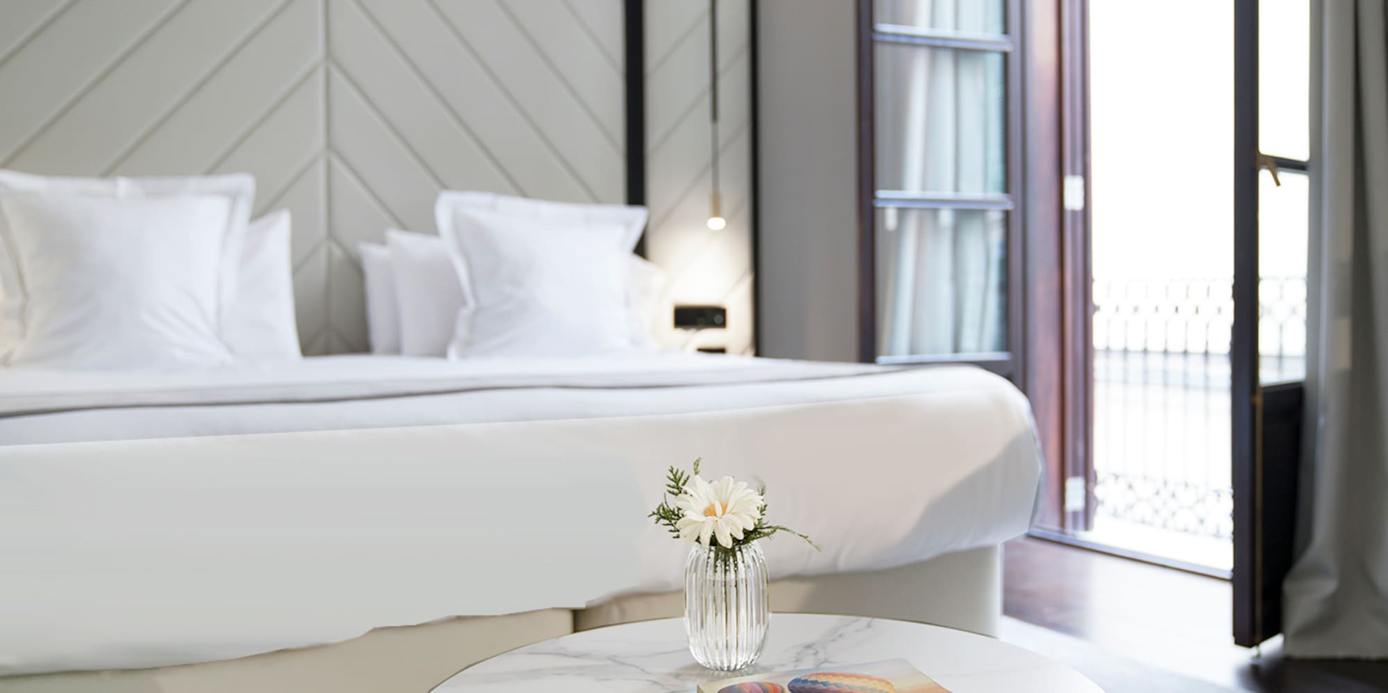 a table with a magazine and a pen in front of a bed