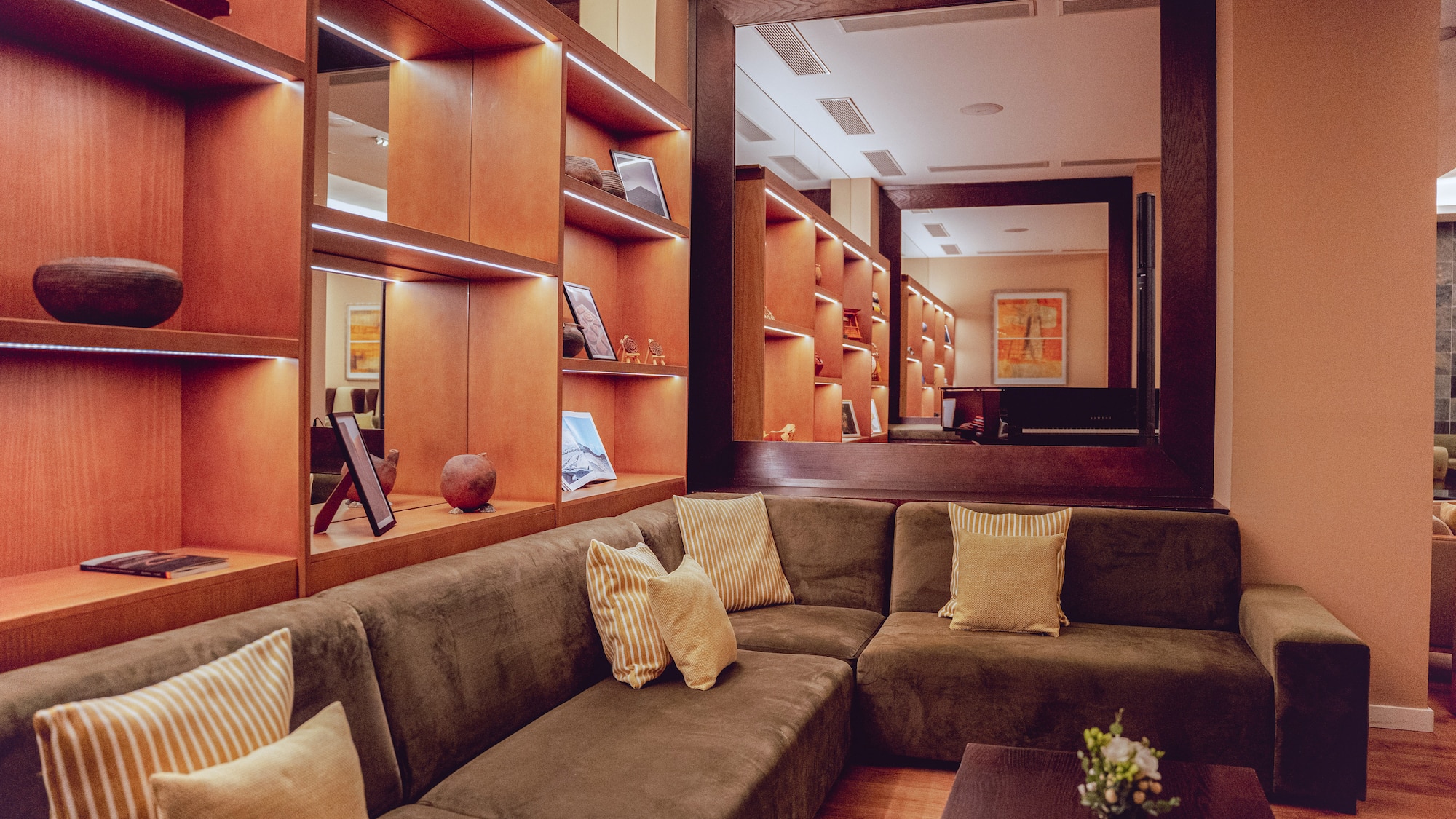 a couch with pillows in a room with shelves and a mirror