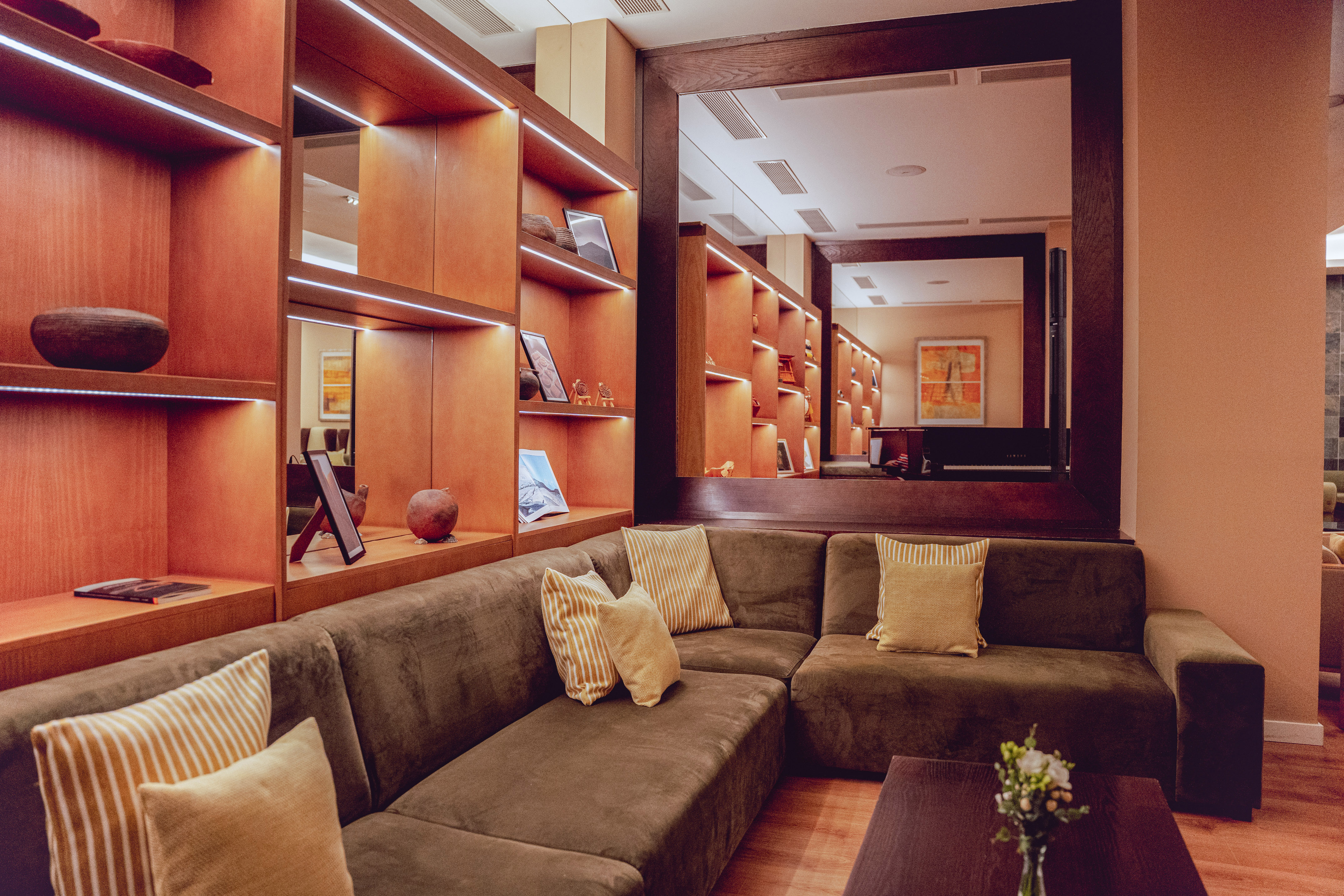 a couch with pillows in a room with shelves and a mirror