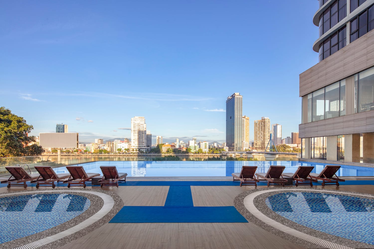 a pool with lounge chairs and a city skyline in the background