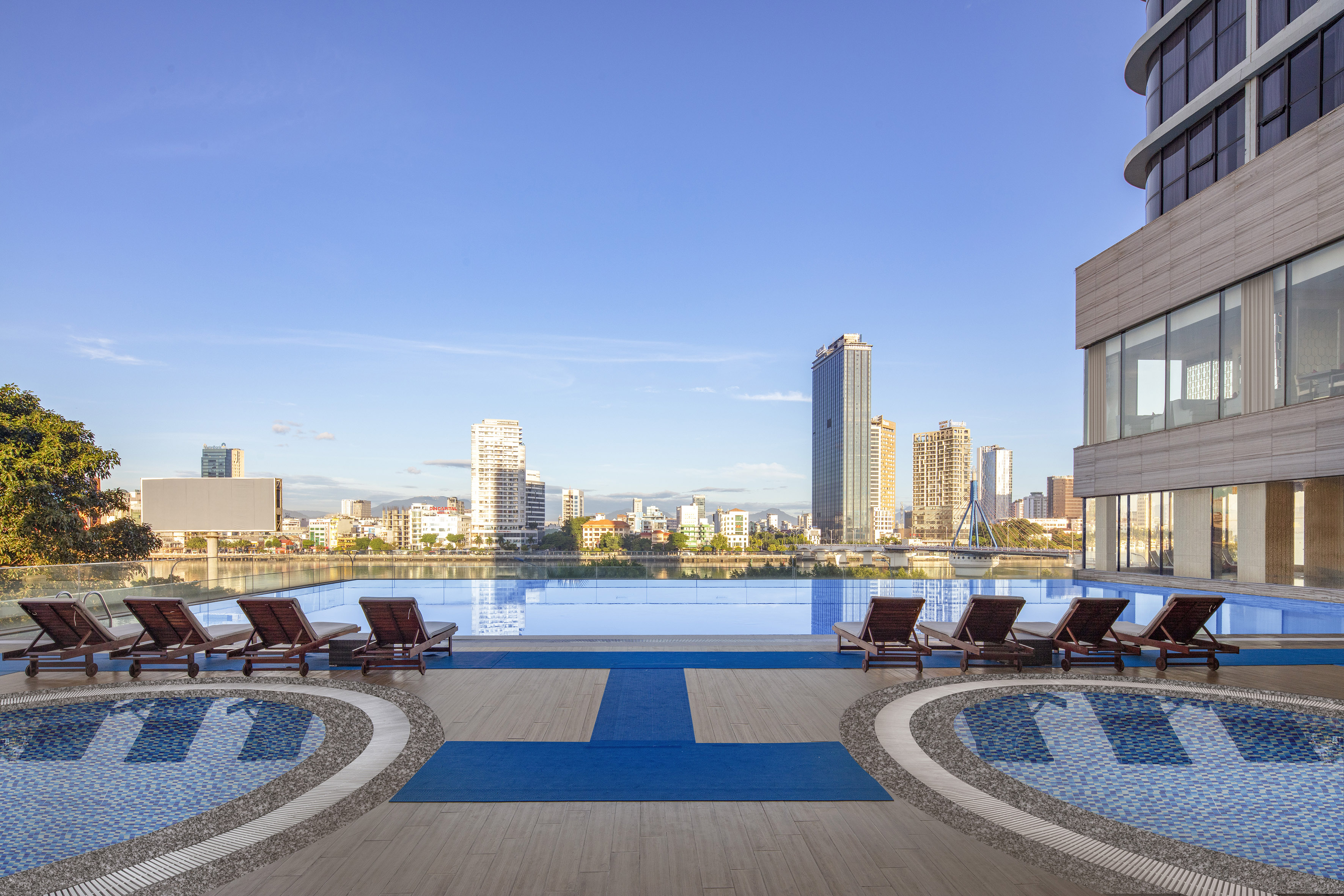 a pool with lounge chairs and a city skyline in the background
