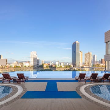 a pool with lounge chairs and a city skyline in the background