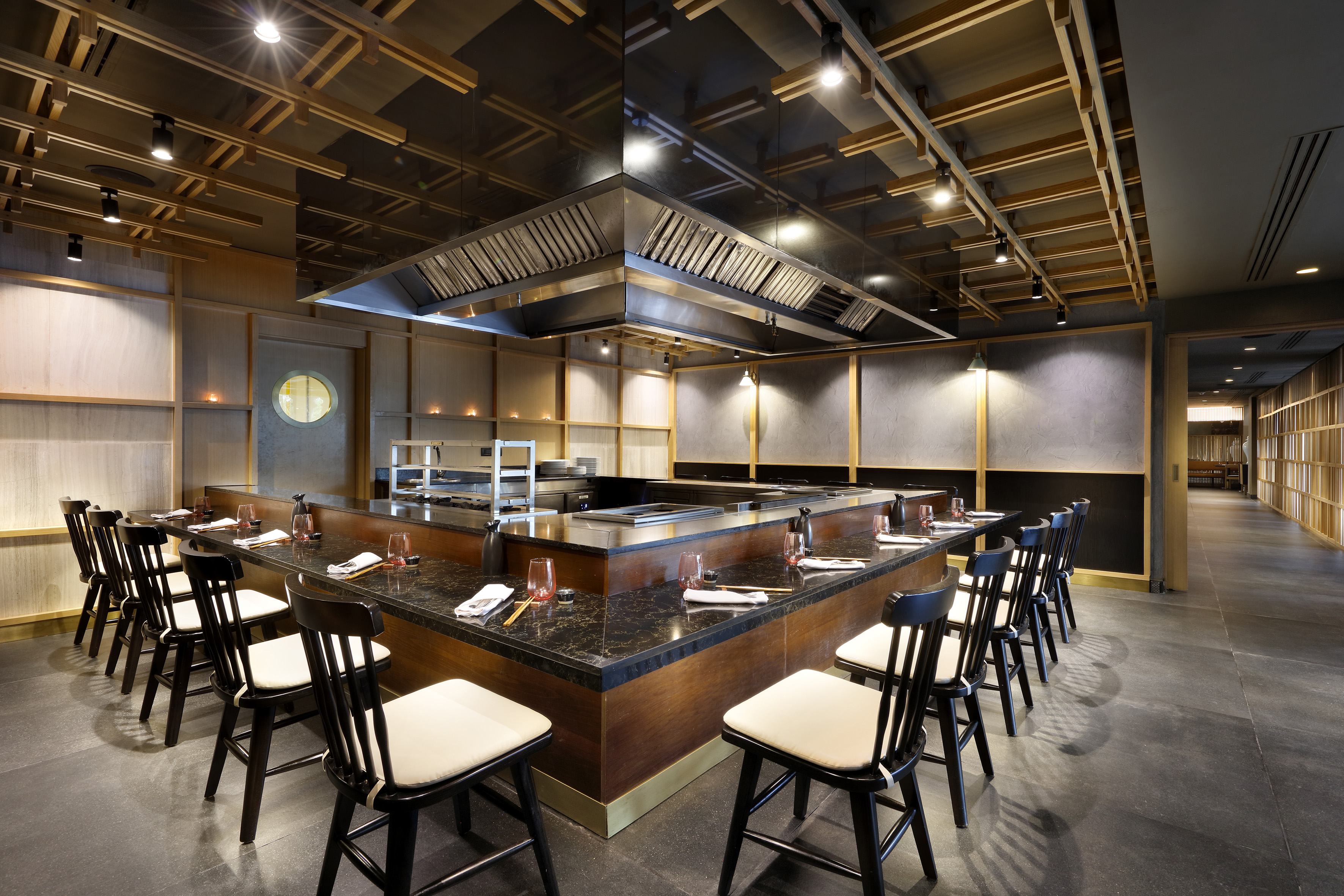 Modern Japanese teppanyaki restaurant interior with central grill and bar seating.