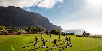 a group of people doing yoga on a grassy field